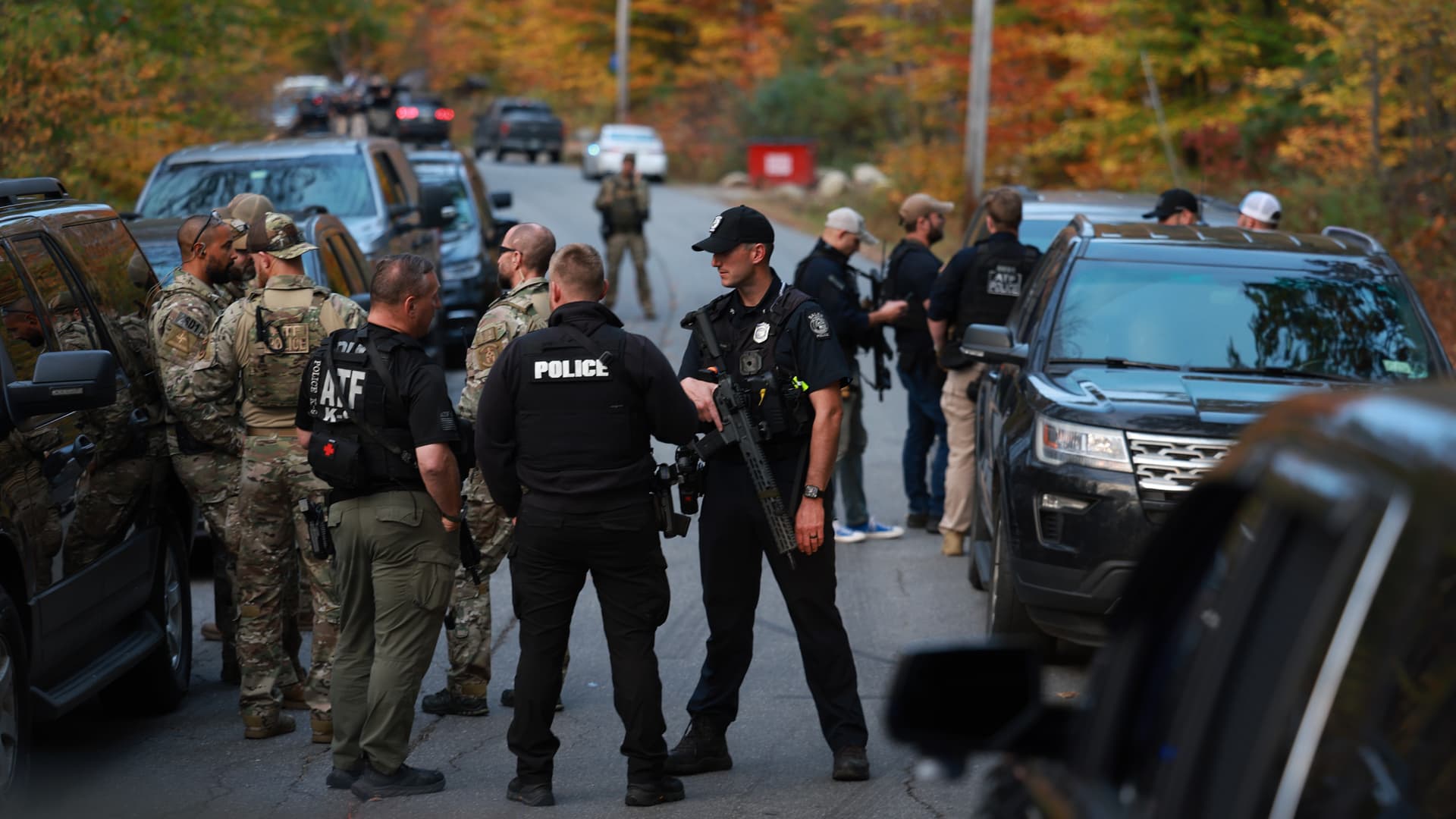 Law enforcement officials gather in the road leading to the home of the suspect being sought in connection with two mass shootings in Bowdoin, Maine, on Oct. 26, 2023.