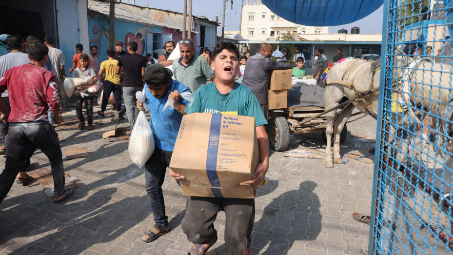 Palestinians collect food from a UN-run aid supply center, distributing food to local Palestinians and people displaced following Israel's call for more than 1 million residents in northern Gaza to move south for their safety, in Deir al-Balah on October 28, 2023, amid the ongoing battles between Israel and the Palestinian group Hamas. Thousands of civilians, both Palestinians and Israelis, have died since October 7, 2023, after Palestinian Hamas militants based in the Gaza Strip entered southern Israel in
