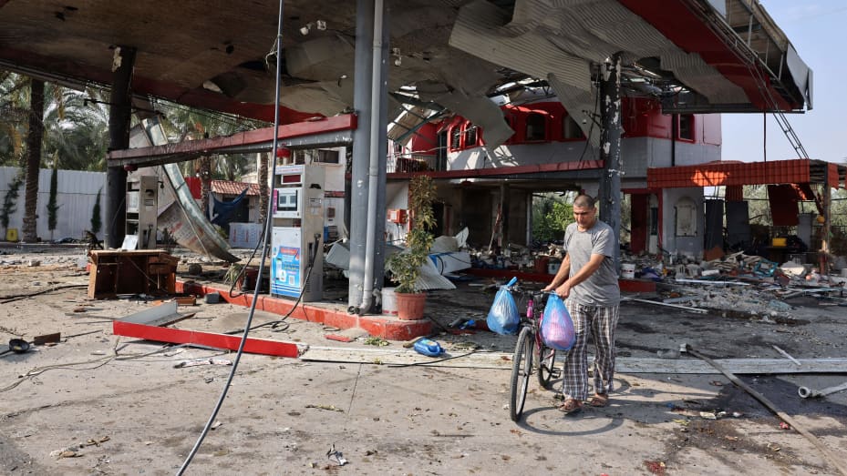 A man pushes his push bike past a gas station destroyed during Israeli bombardment in Khan Yunis refugee camp, in Khan Yunis in the southern Gaza Strip on October 28 , 2023, amid the ongoing battles between Israel and the Palestinian group Hamas. 