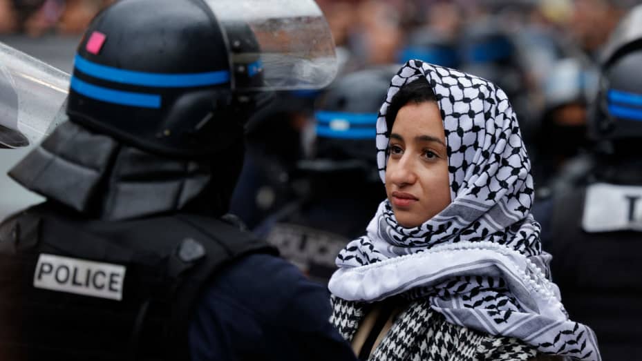 A protester faces a French police officer in riot gear during a demonstration in support to Palestinians in central Paris on October 28, 2023.