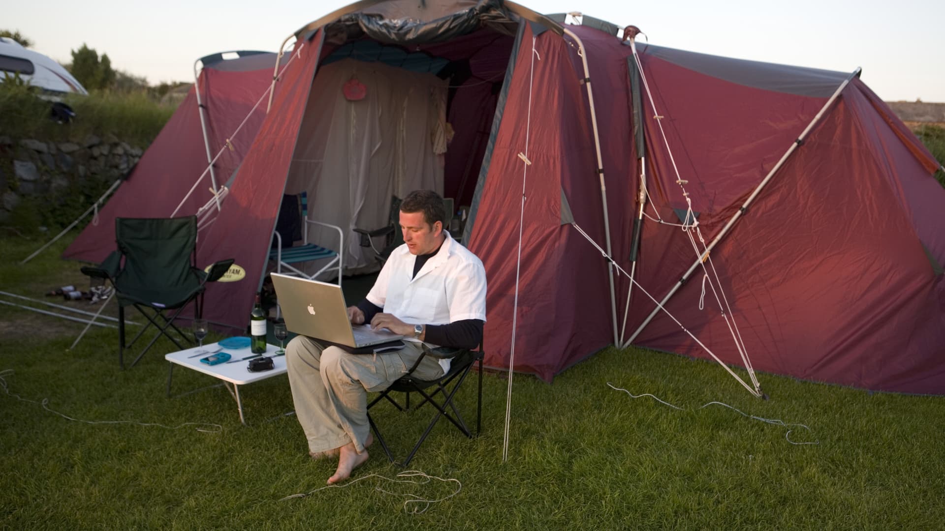 A camper takes some time to work on his laptop while on a family camping holiday.