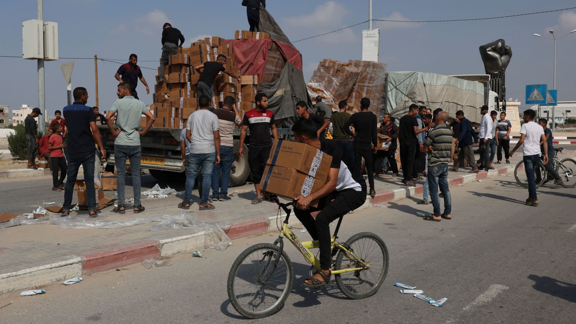 A young man carries aid parcels on his bicycle as other reload fallen boxes onto a truck carrying humanitarian aid that entered the southern Gaza Strip from Egypt via the Rafah border crossing on November 2, 2023, as battles between Israel and the Palestinian Hamas movement continue. (Photo by Mohammed ABED / AFP) (Photo by MOHAMMED ABED/AFP via Getty Images)