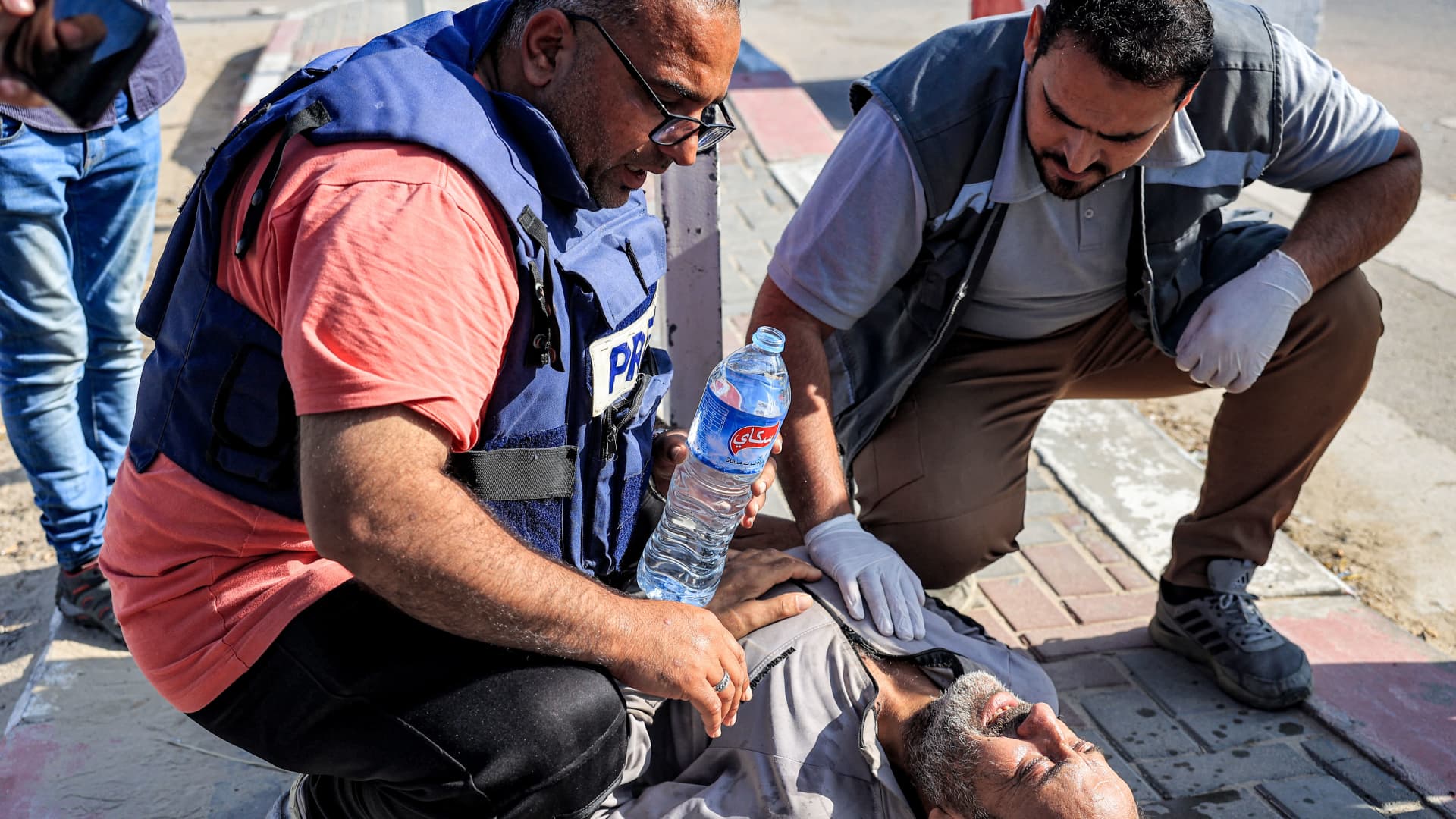 A journalist and paramedic assist one of the Palestinian workers who were stranded in Israel since the October 7 attacks after he collapsed upon arriving at the Rafah border crossing with Egypt after crossing into the Gaza Strip at the Kerem Shalom commercial border crossing with Israel in the south of the Palestinian enclave on November 3, 2023.