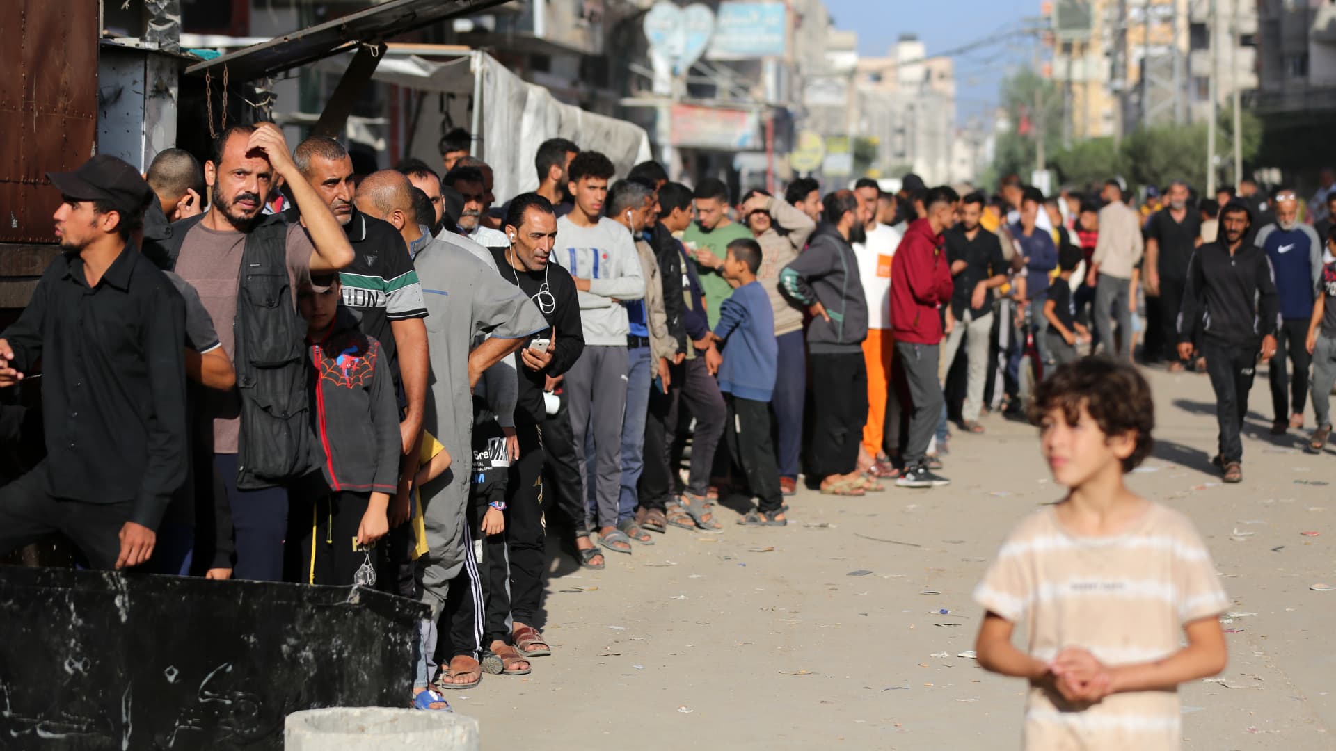 People queue for bread in front of a bakery that was partially destroyed in an Israeli strike, in the Nuseirat refugee camp in the central Gaza Strip, on November 4, 2023, as battles continue between Israel and the Palestinian Hamas movement.