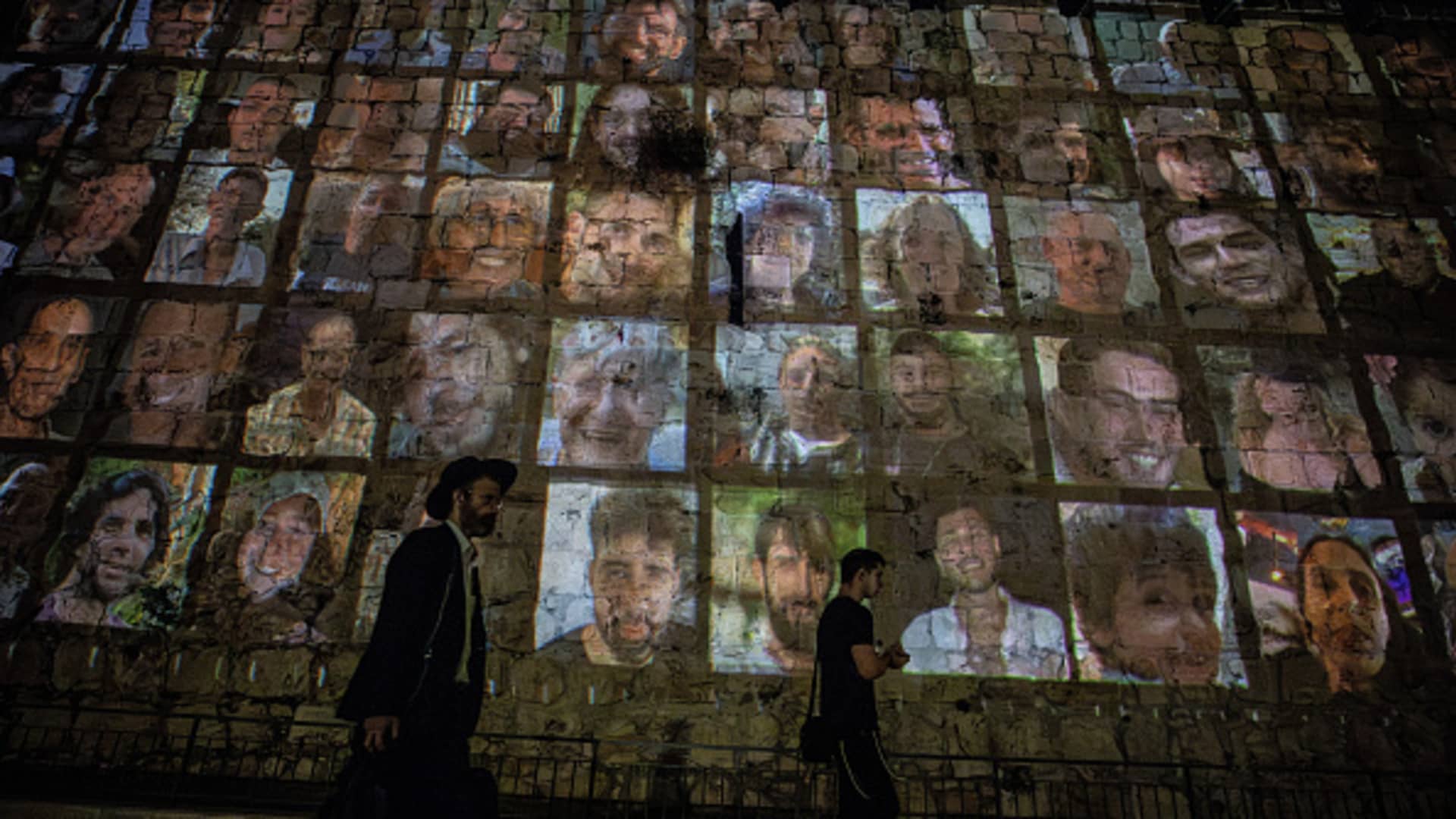 Photographs of Israelis taken hostage by Hamas in the Gaza Strip, are reflected on the walls of Jerusalem at the Old City in Jerusalem on November 06, 2023. 