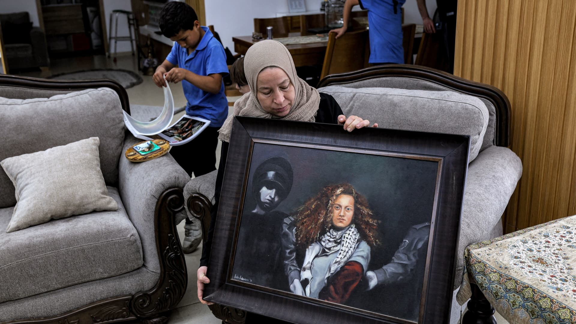 Nariman Tamimi, mother of detained Palestinian activist Ahed Tamimi, holds a framed painting depicting her daughter as she sits in their family home in the village of Nabi Saleh in the occupied West Bank on November 6, 2023. 