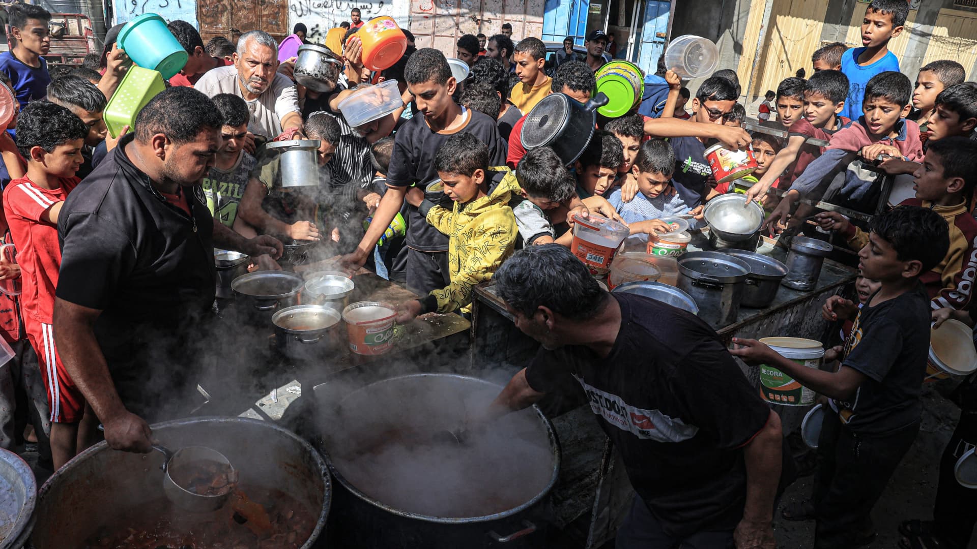 Palestinians queue to receive a portion of food at a make-shift charity kitchen in Rafah in the southern Gaza Strip, on November 8, 2023, amid the ongoing battles between Israel and the militant group Hamas. 