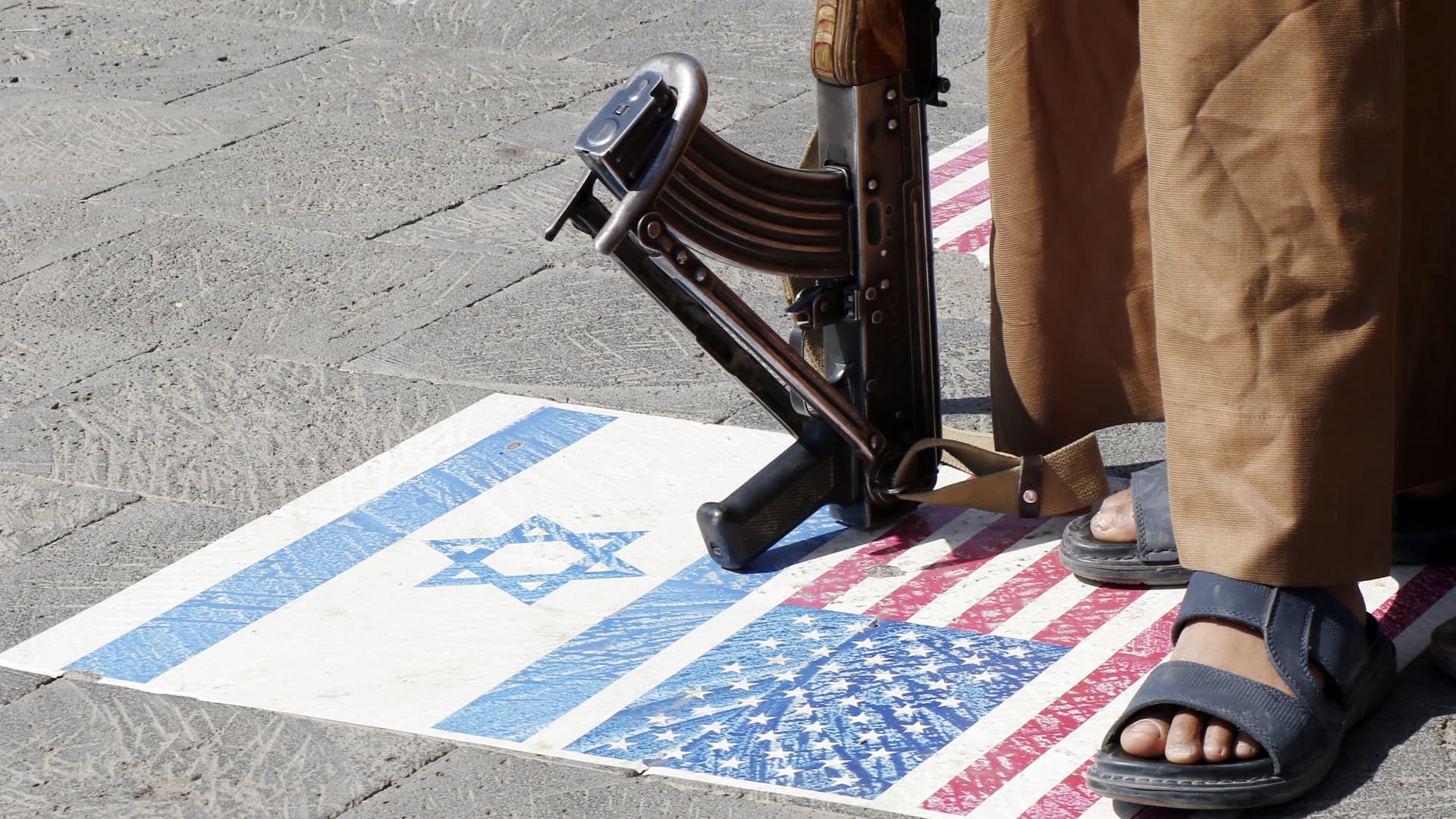 A Yemeni Houthi supporter walking on U.S. and Israeli flags painted in solidarity with Palestinians, visit the tomb of Saleh al-Samad, the former Houthi-founded Supreme Political Council's president, on November 09, 2023 in Sana'a, Yemen.