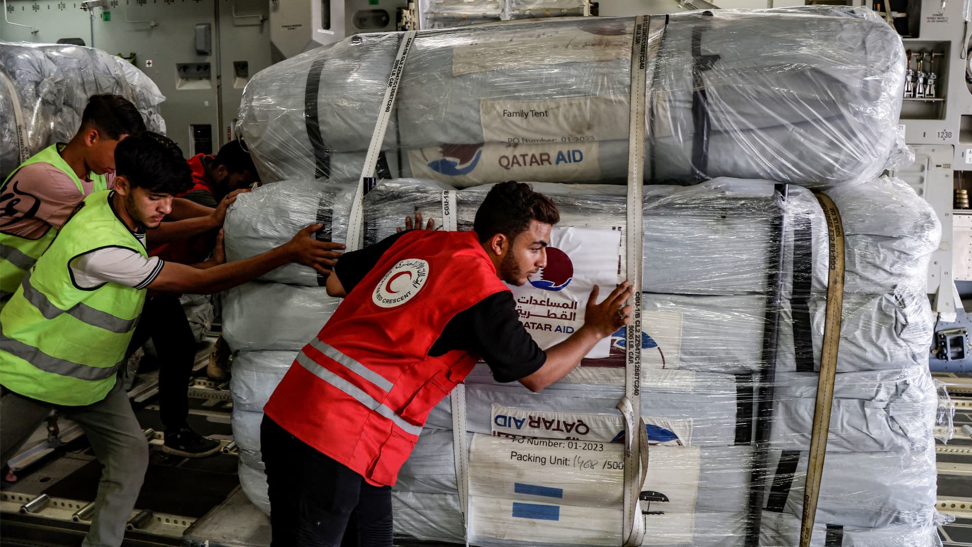 An Egyptian Red Crescent member and other workers unload a shipment of humanitarian aid bound for the Gaza Strip off a Qatar Emiri Air Force C-17 Globemaster III military transport aircraft after landing at Arish International Airport in North Sinai province in northeastern Egypt on November 9, 2023 amid ongoing fighting between Israel and the Palestinian group Hamas.
