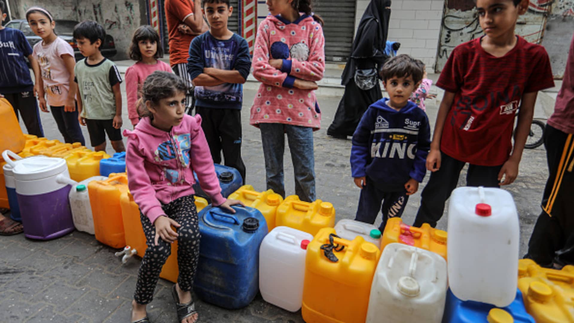 Palestinian children fill containers with water in Rafah, in the southern Gaza Strip on November 13, 2023, amid the ongoing battles between Israel and the Palestinian militant group Hamas. 