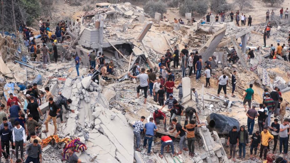 TOPSHOT - Civiles y rescatistas buscan sobrevivientes entre los escombros de un edificio destruido luego de un bombardeo israelí en Khan Yunis, en el sur de la Franja de Gaza, el 12 de noviembre de 2023, en medio de las batallas en curso entre Israel y el grupo militante palestino Hamas.  Más de 10.000 personas han muerto en los incesantes bombardeos israelíes de la Franja de Gaza, según el Ministerio de Salud dirigido por Hamás, desde que estalló la guerra el mes pasado después de que militantes palestinos atacaran el sur de Israel el 7 de octubre matando