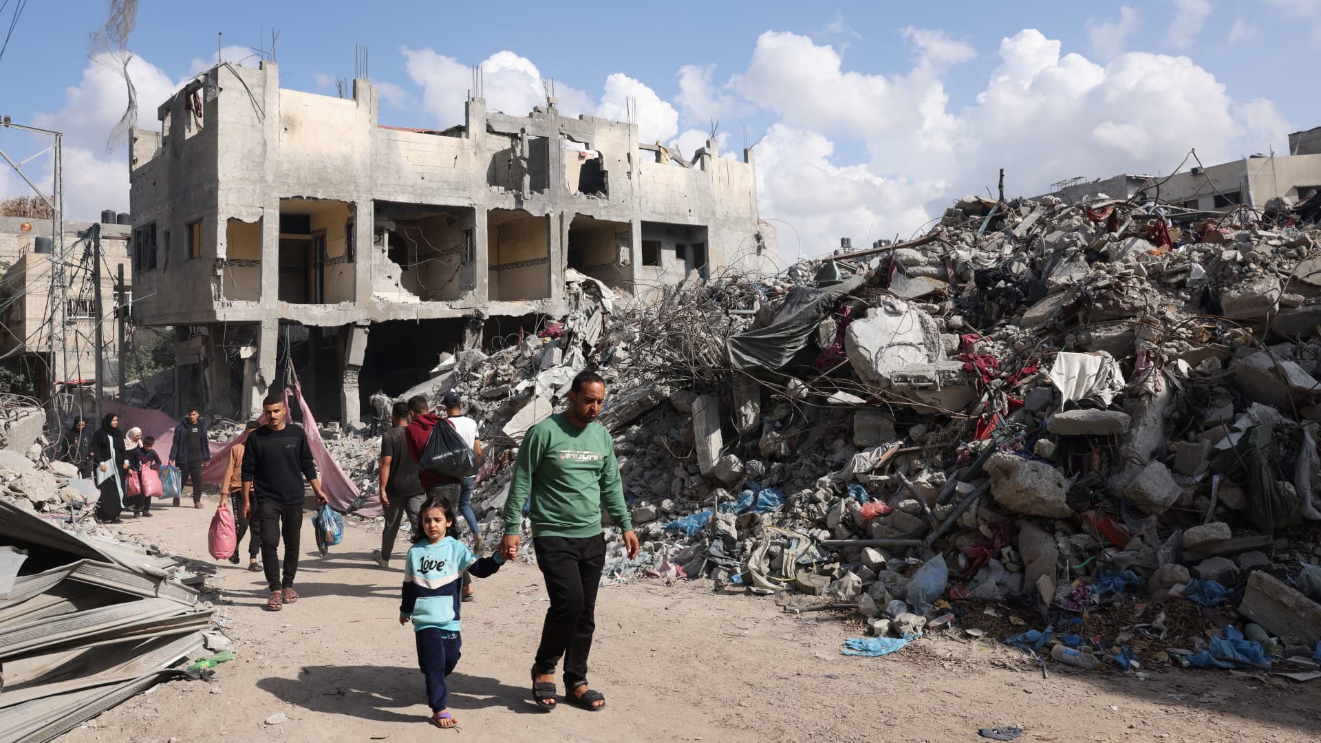 Palestinian families walks past destroyed buildings in Bureij, in the central of Gaza Strip, on November 14, 2023, amid the ongoing battles between Israel and the Palestinian group Hamas. (Photo by MOHAMMED ABED / AFP) (Photo by MOHAMMED ABED/AFP via Getty Images)