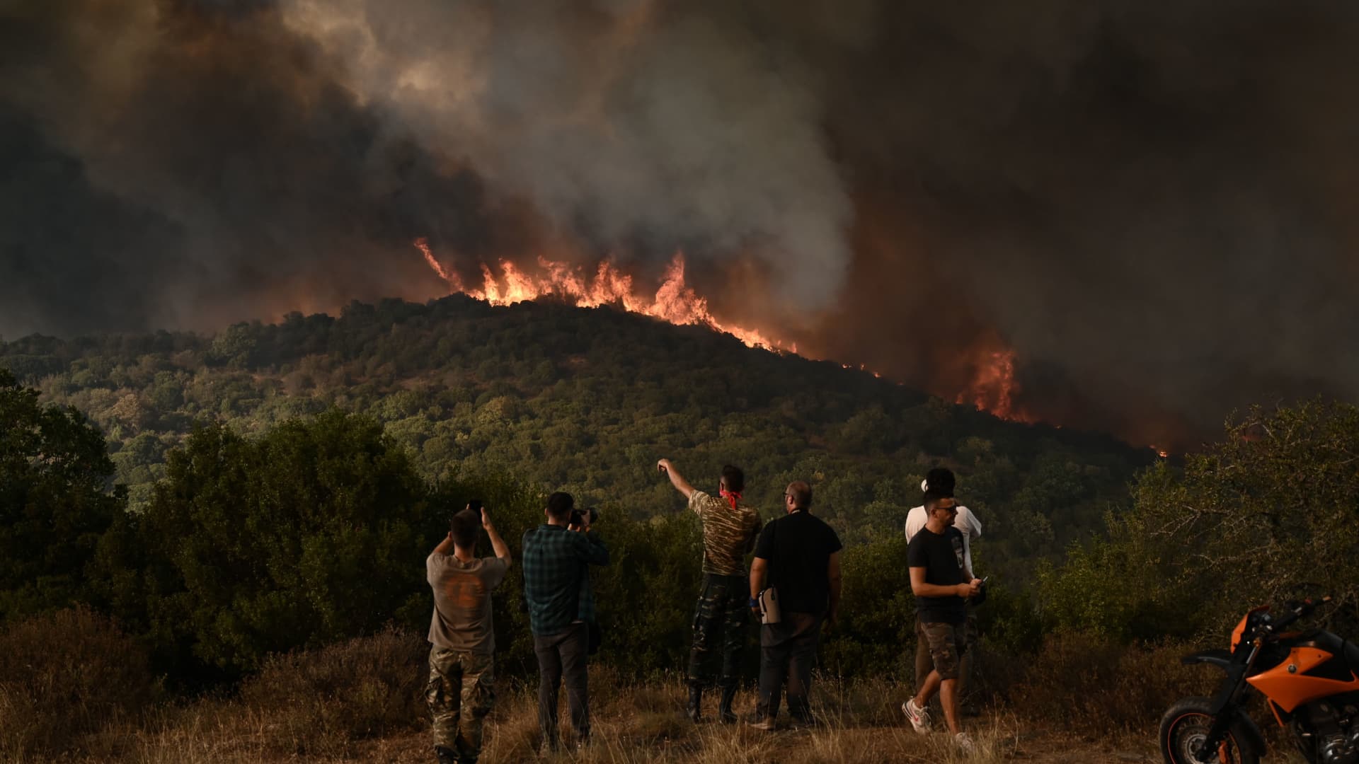 People look at the wildfire raging in a forest in Sikorahi, near Alexandroupoli, northern Greece, on August 23, 2023.
