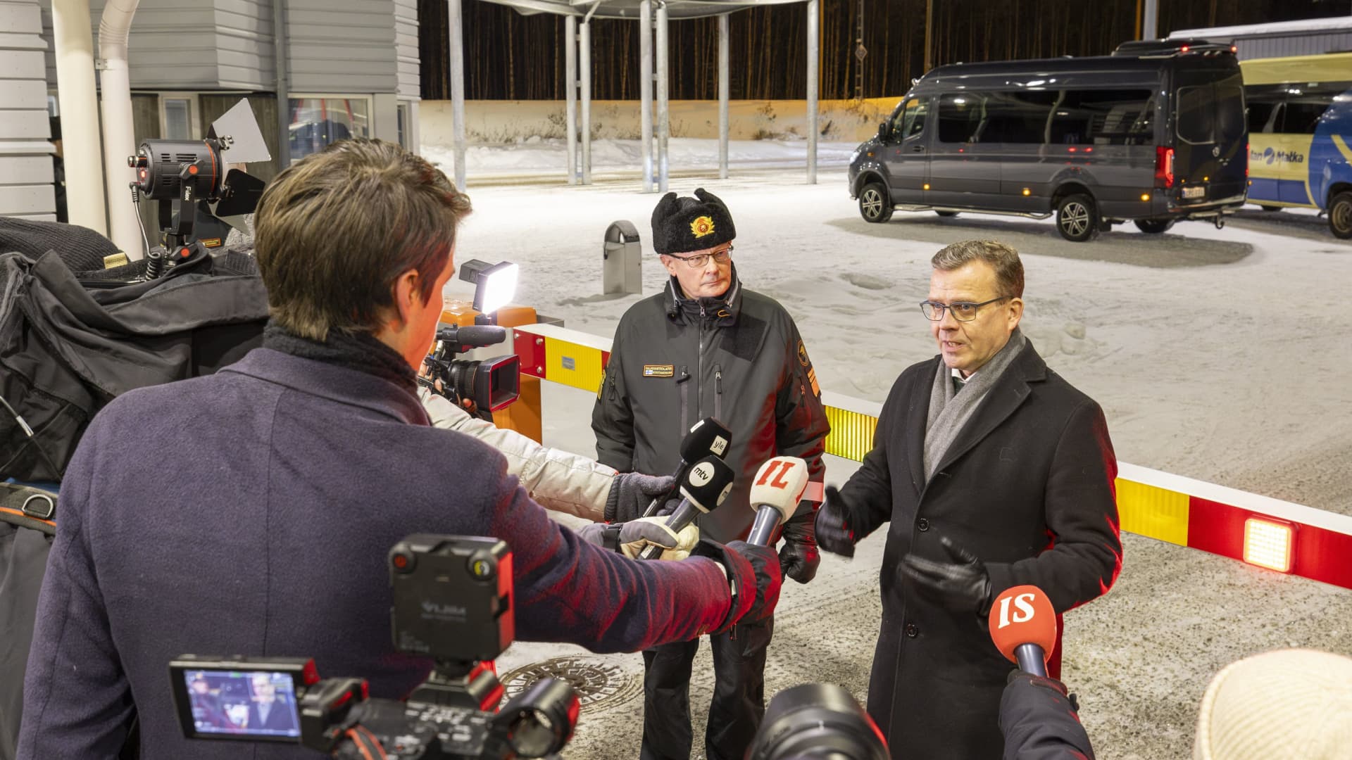 Chief of the Finnish Border Guard, Lieutenant General Pasi Kostamovaara (L) looks on as Finnish Prime Minister Petteri Orpo speaks at a press briefing during his visit to the Vartius border crossing station in Kuhmo, eastern Finland, on November 20, 2023.