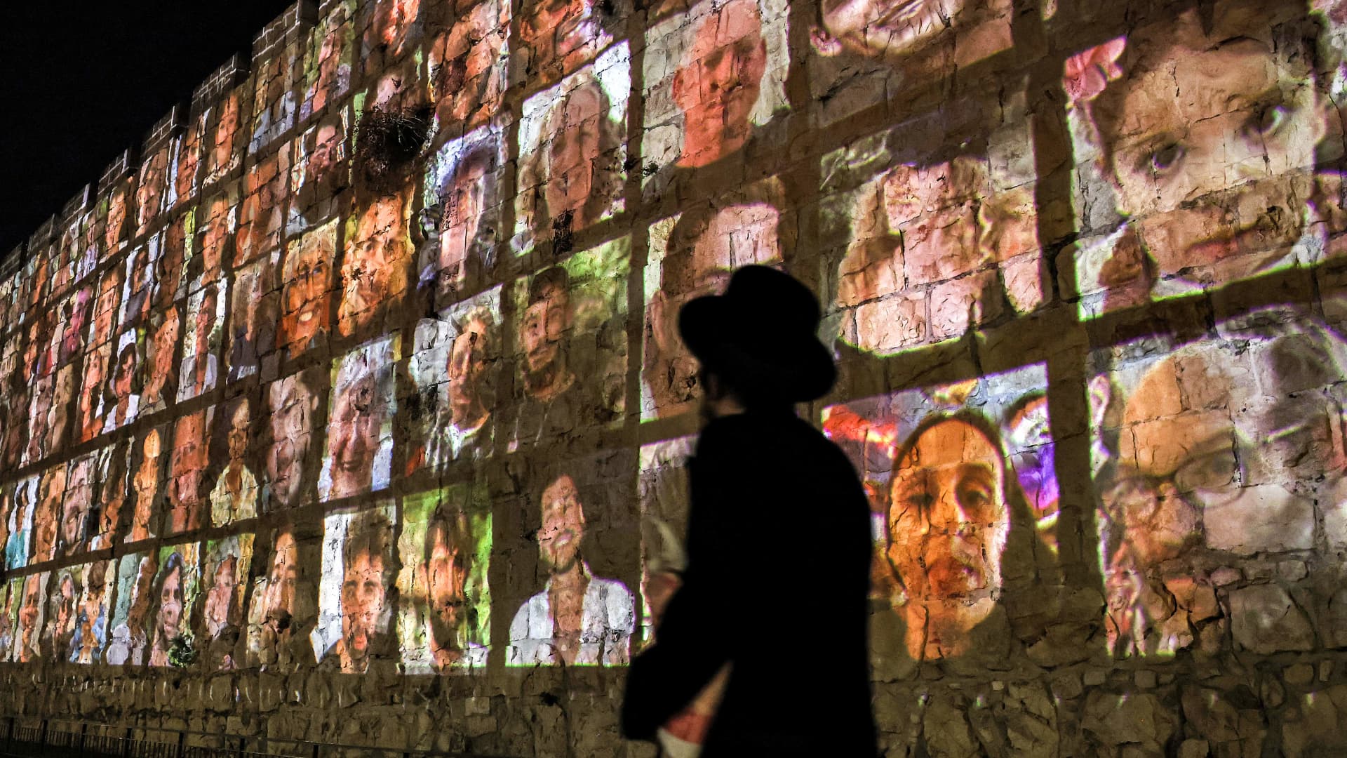 An Ultra-Orthodox Jewish man walks outside the walls of the old city of Jerusalem, on which are projected pictures of the hostages abducted by Palestinian militants on the October 7 attack and currently held in the Gaza Strip, on November 6, 2023, amid the ongoing battles between Israel and the militant group Hamas.