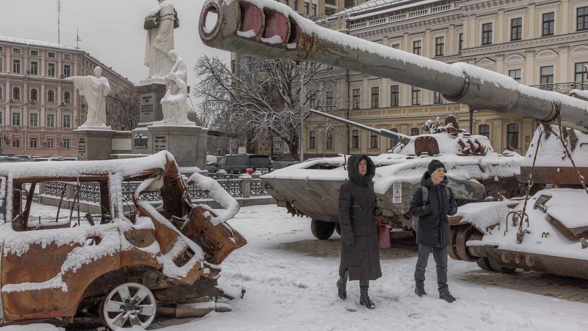 Pedestrians walks past destroyed Russian military vehicles blanketed in snow in front of Saint Michael's Golden-Domed Monastery, in downtown Kyiv, on November 22, 2023.