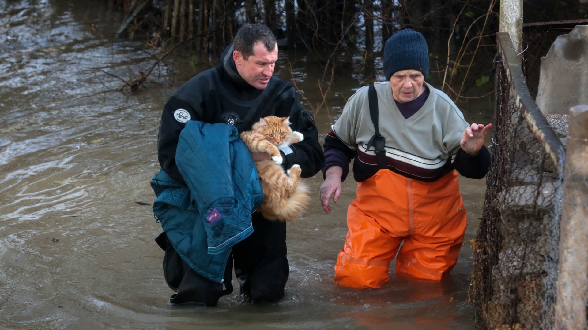 A rescuer carries a cat and helps a woman during an evacuation of residents of the flooded village of Pribrezhnoe in Crimea on November 27, 2023, following a storm. Over 400,000 people in Crimea were left without power on November 27, 2023 after hurricane force winds and heavy rains battered the Russian-annexed peninsula over the weekend. Wind speeds of more than 140 kilometres per hour (about 90 mph) were recorded during the storm, which triggered a state of emergency in some of the peninsula's municipalities. (Photo by STRINGER / AFP) (Photo by STRINGER/AFP via Getty Images)
