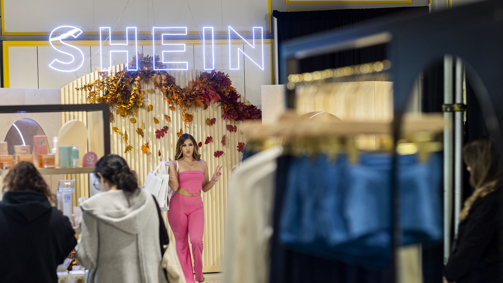 Shoppers Ashley Sanchez, center, of Fontana, poses for her friend Joscelin Flores, not pictured, who was taking photos with their bags of merchandise after being among the first group of shoppers taking the opportunity to shop on the opening day of fast fashion e-commerce giant Shein, which is hosting a brick-and-mortar pop up inside Forever 21 at the Ontario Mills Mall in Ontario Thursday, Oct. 19, 2023.(Allen J. Schaben / Los Angeles Times via Getty Images)