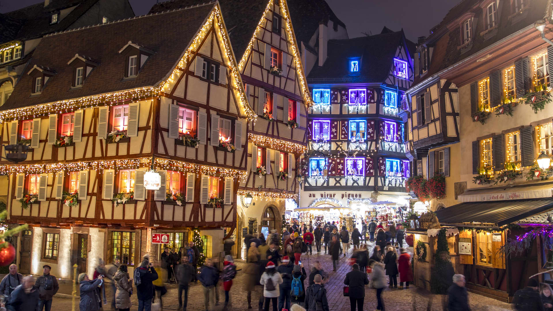Half-timbered houses in Colmar adorned with Christmas lights during the holiday season.
