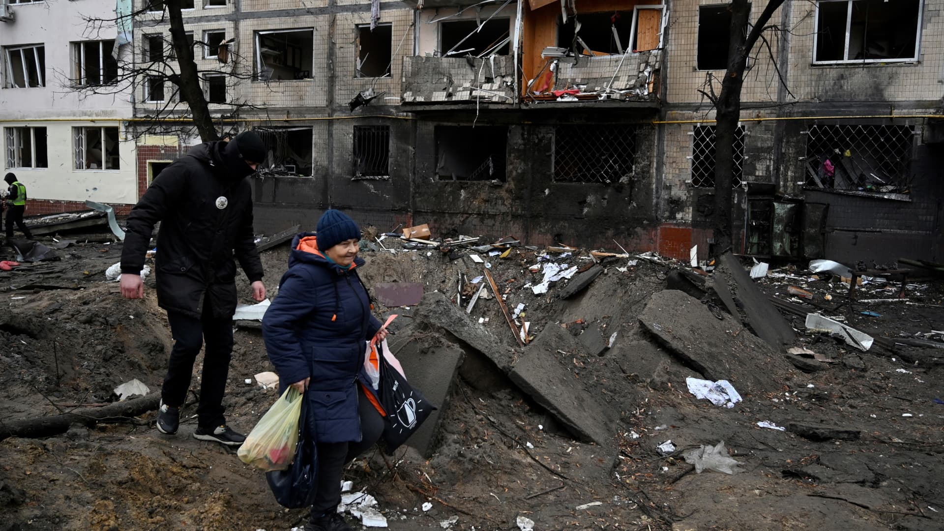 People walk past a damaged residential building following a missile strike in Kyiv on December 13, 2023, amid Russian invasion of Ukraine. (Photo by SERGEI CHUZAVKOV / AFP) (Photo by SERGEI CHUZAVKOV/AFP via Getty Images)