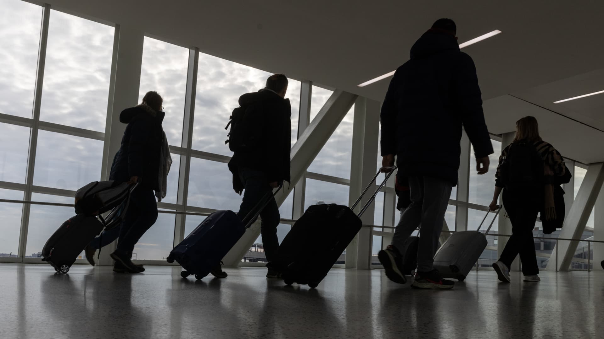 Travelers walk with their luggage at John F. Kennedy International Airport in New York on Dec. 23, 2023.