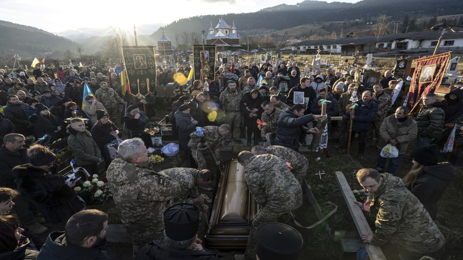 Ukrainian servicemen lower the coffin of Ukrainian army officer into a grave at a cemetery in the Carpathian mountains in Krasnyk village, Ukraine, on Friday, Dec. 29, 2023.
