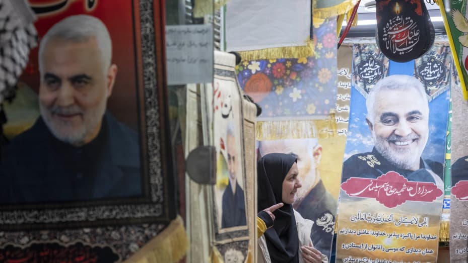 An Iranian woman is standing next to flags featuring portraits of the Islamic Revolutionary Guard Corps' (IRGC) Quds Force, Major General Qasem Soleimani, in a war toys and religious accessory shopping mall in downtown Tehran, on the anniversary of the killing of Qassem Soleimani at Baghdad Airport by the United States, on December 30, 2023. (Photo by Morteza Nikoubazl/NurPhoto via Getty Images)