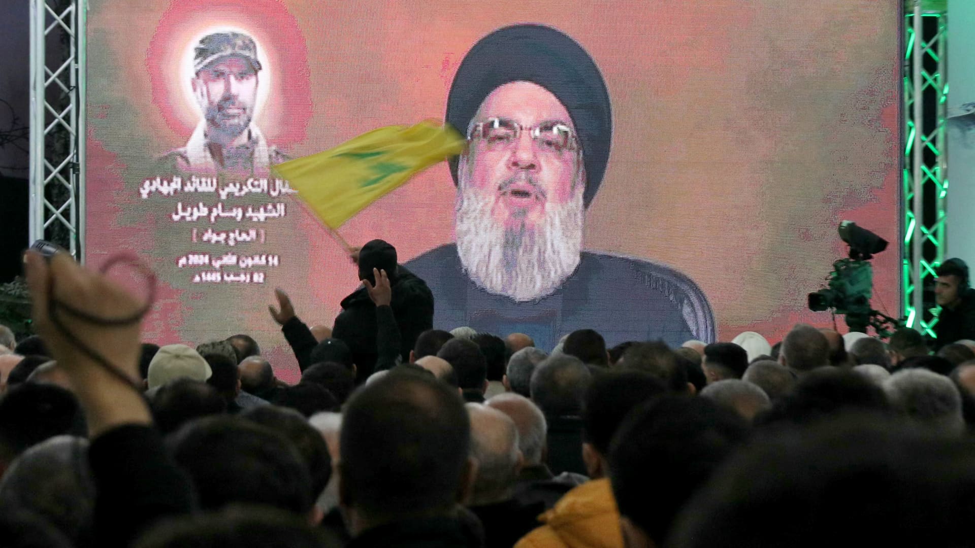A man waves a Hezbollah movement flag as its leader Hassan Nasrallah delivers a televised speech in Kherbet Selm in southern Lebanon on January 14, 2024, marking the one week memorial since the killing top field commander Wissam Tawil.