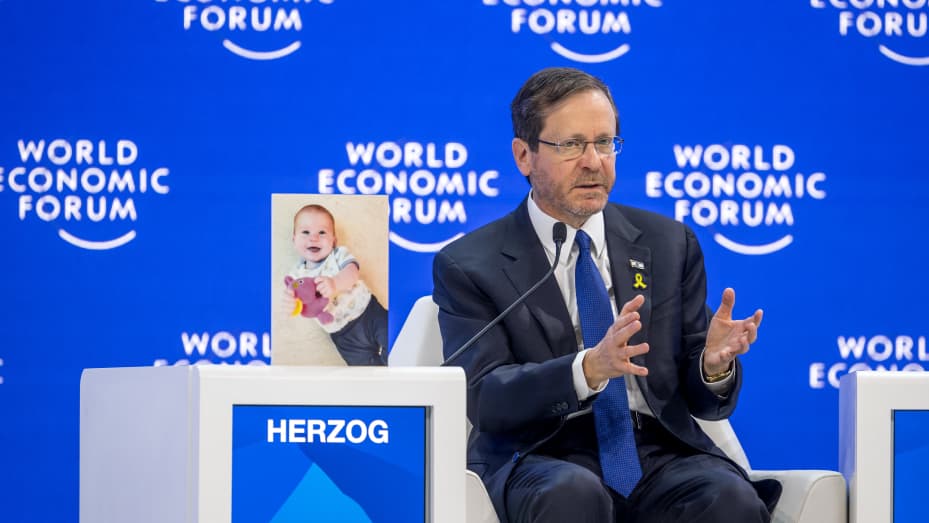 Israeli President Isaac Herzog gestures as he sits next to a photograph showing 10-month-old baby Kfir Bibas held by Hamas during a session of the World Economic Forum (WEF) meeting in Davos on January 18, 2024.