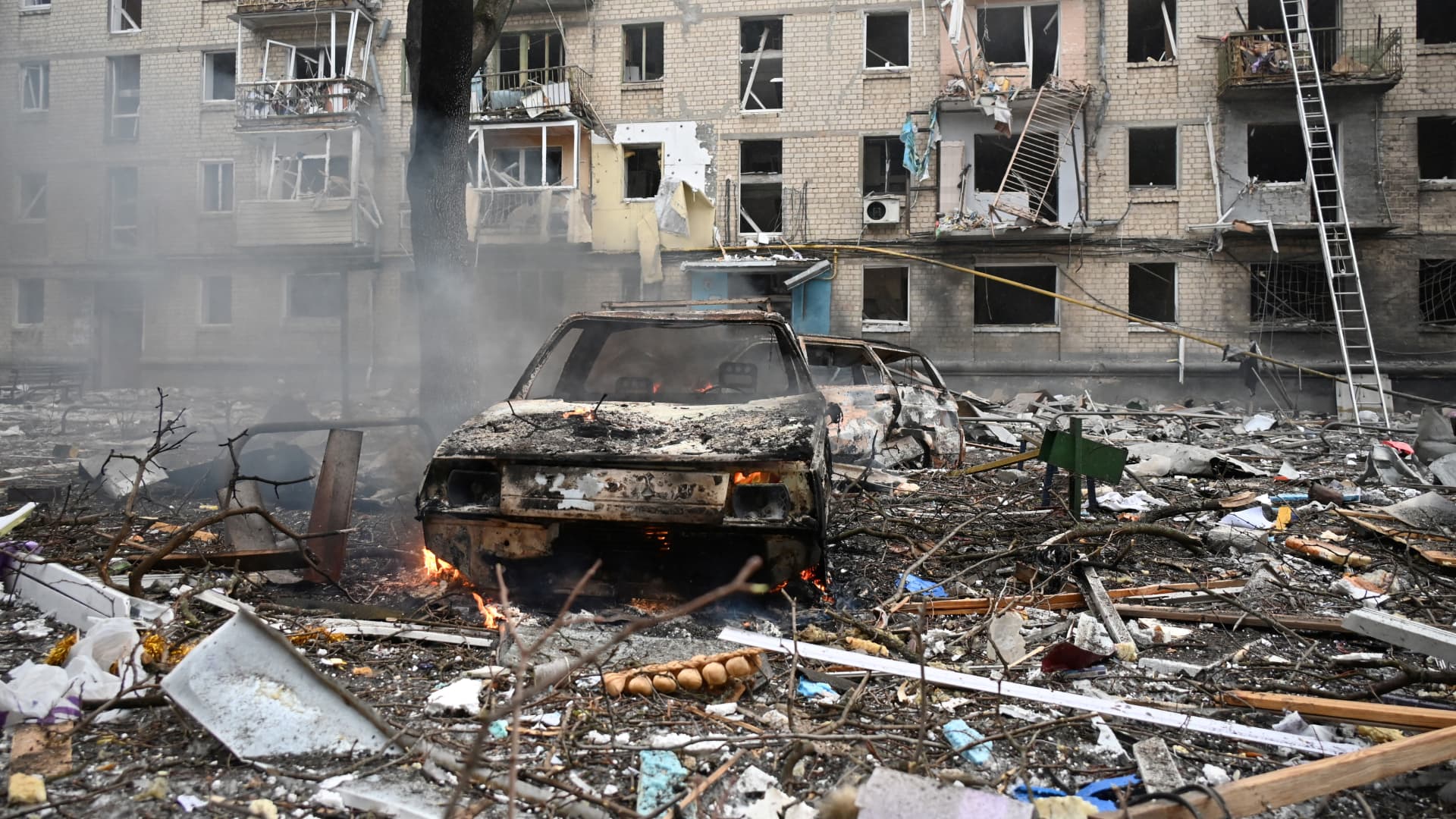 TOPSHOT - This photograph taken on January 23, 2024 shows destroyed vehicles in front of a residential building destroyed as a result of a missile attack in Kharkiv. Dozens of people were injured and two killed following an overnight aerial barrage by Russian forces targeting the Ukrainian capital Kyiv and the second-largest city Kharkiv, officials said on January 23, 2024. (Photo by SERGEY BOBOK / AFP) (Photo by SERGEY BOBOK/AFP via Getty Images)