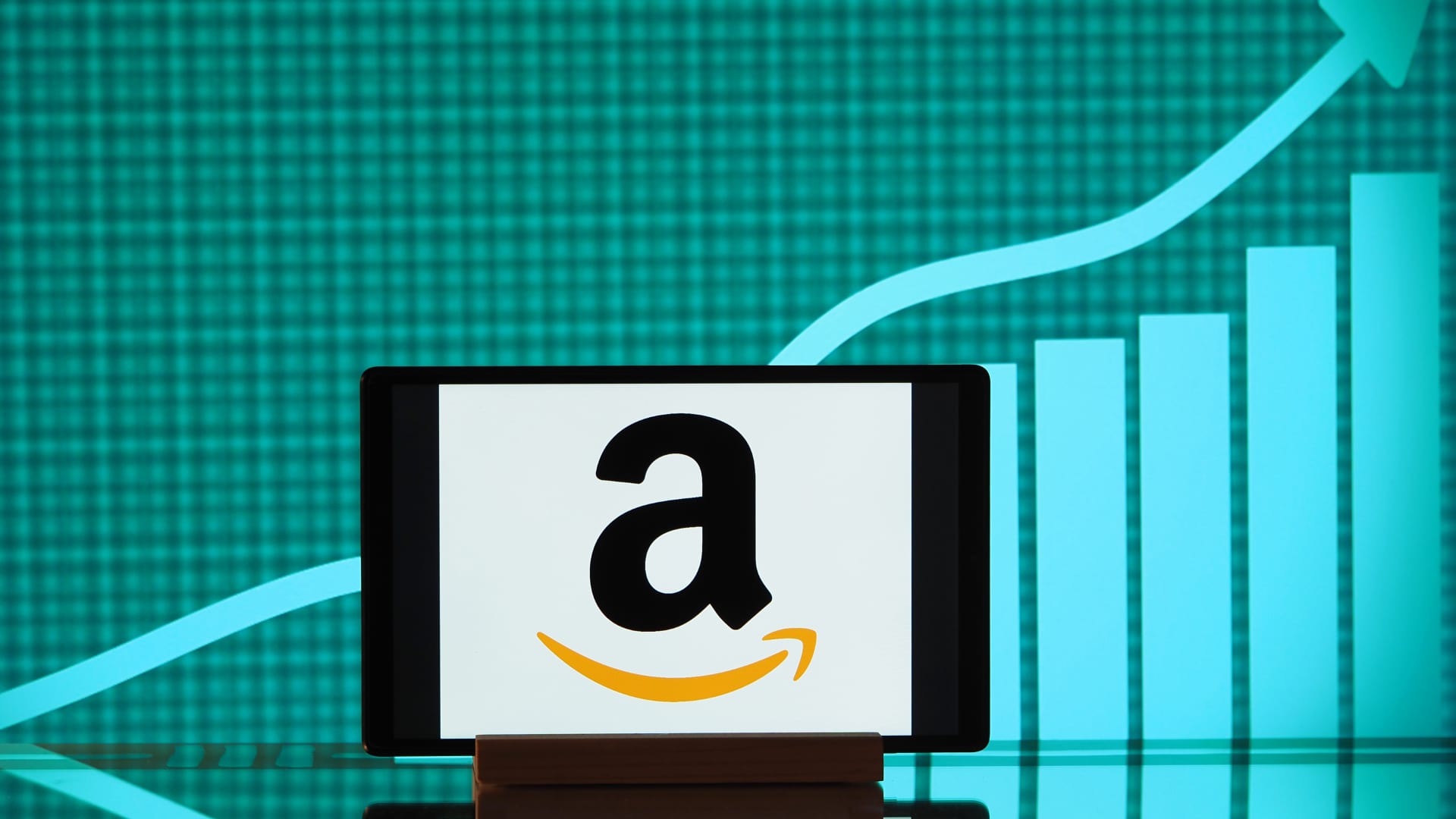 In this photo illustration, the Amazon logo seen displayed on a smartphone screen with a graph in the background.