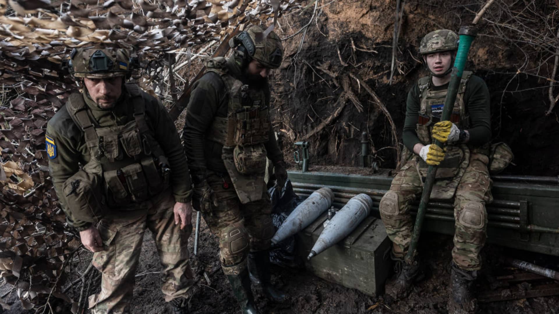 A Ukrainian soldier sits next to artillery shells await firing orders in the direction of Kreminna, in Donetsk Oblast, Ukraine, on February 14, 2024. 