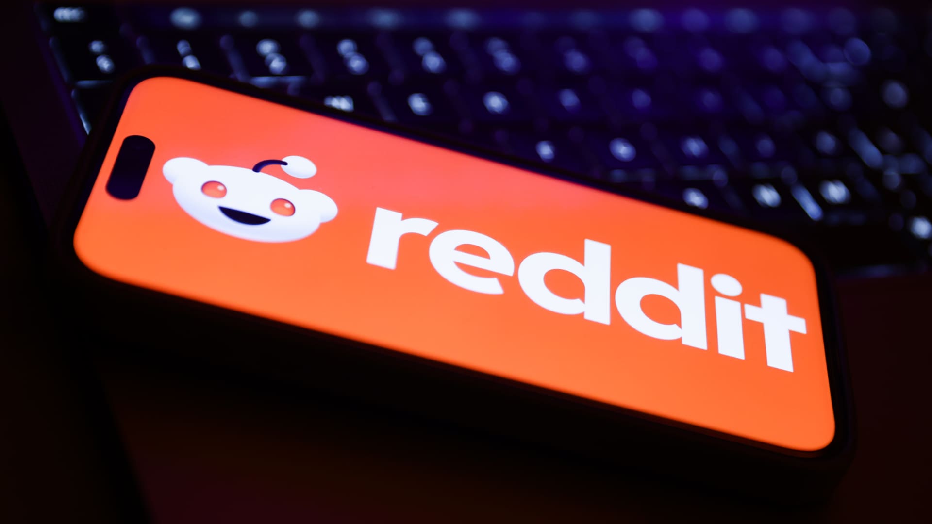 A laptop keyboard and Reddit logo displayed on a phone screen are seen in this illustration photo taken in Krakow, Poland on February 22, 2024.