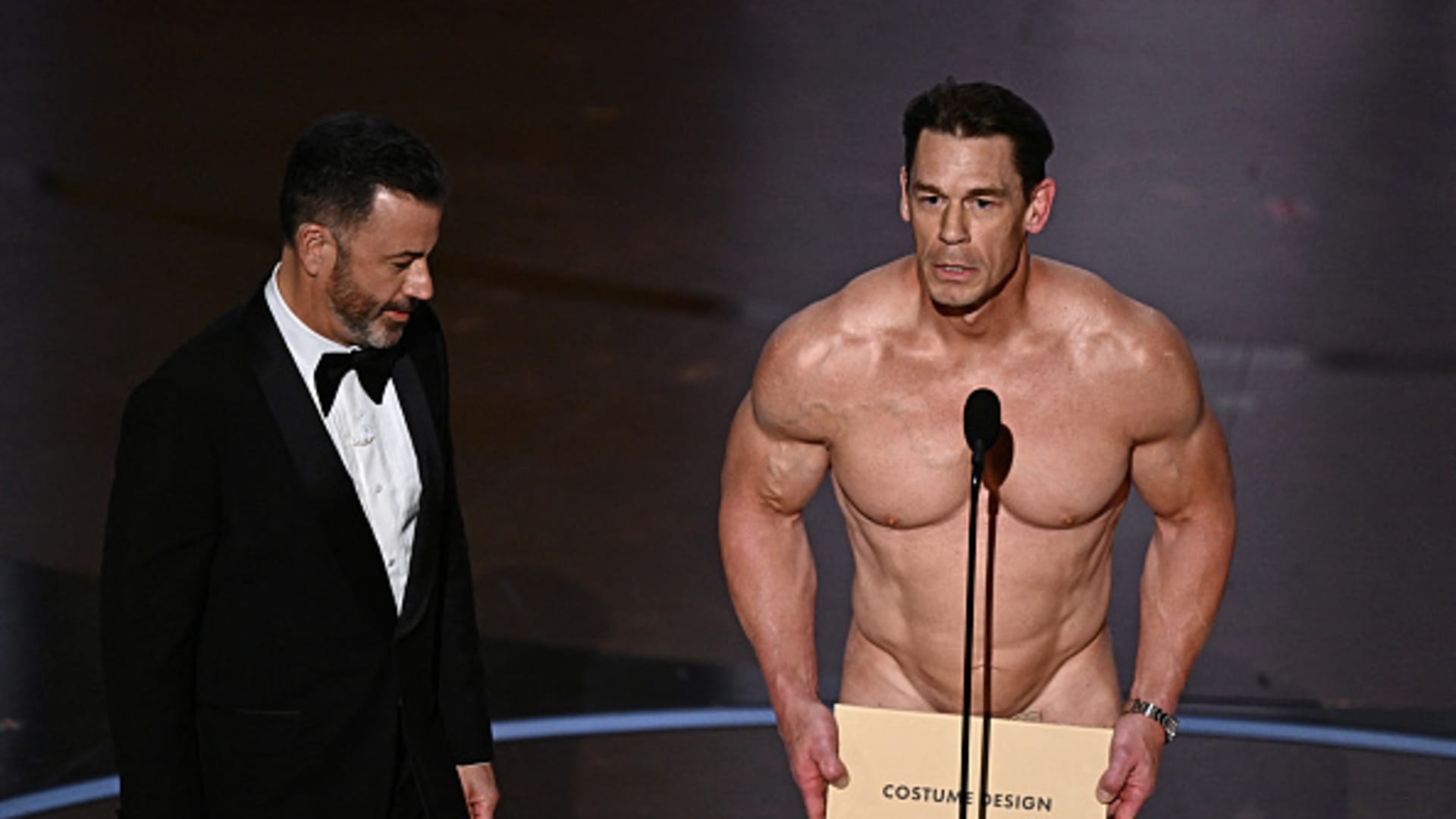 TV host Jimmy Kimmel (L) looks on as US actor John Cena (R) presents the award for Best Costume Design onstage during the 96th Annual Academy Awards at the Dolby Theatre in Hollywood, California on March 10, 2024.=