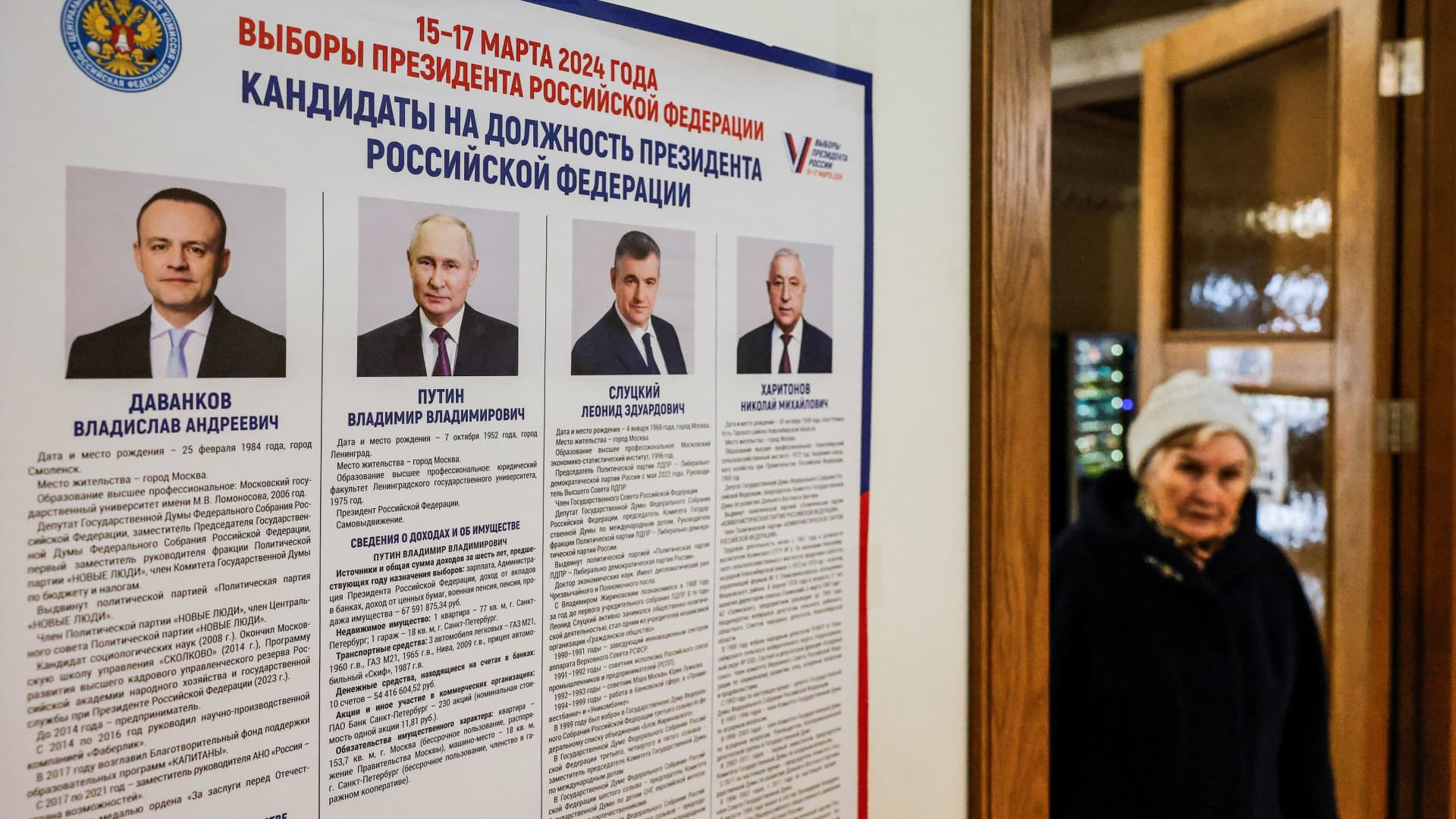 A woman walks past a board with information about candidates at a polling station during the Russian presidential election in Vidnoye, Moscow Region, Russia March 15, 2024. 