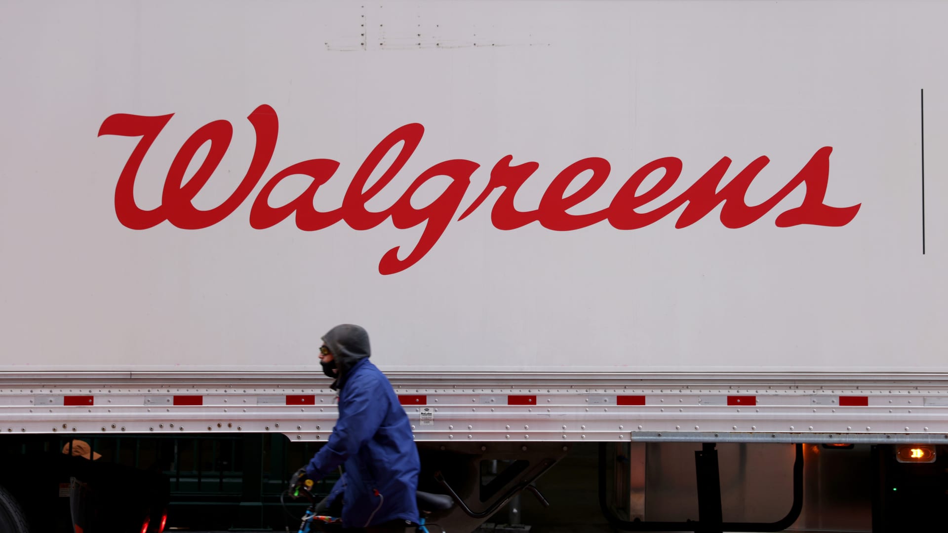 A person rides past a Walgreens truck, owned by the Walgreens Boots Alliance, in Manhattan, New York City, on Nov. 26, 2021.