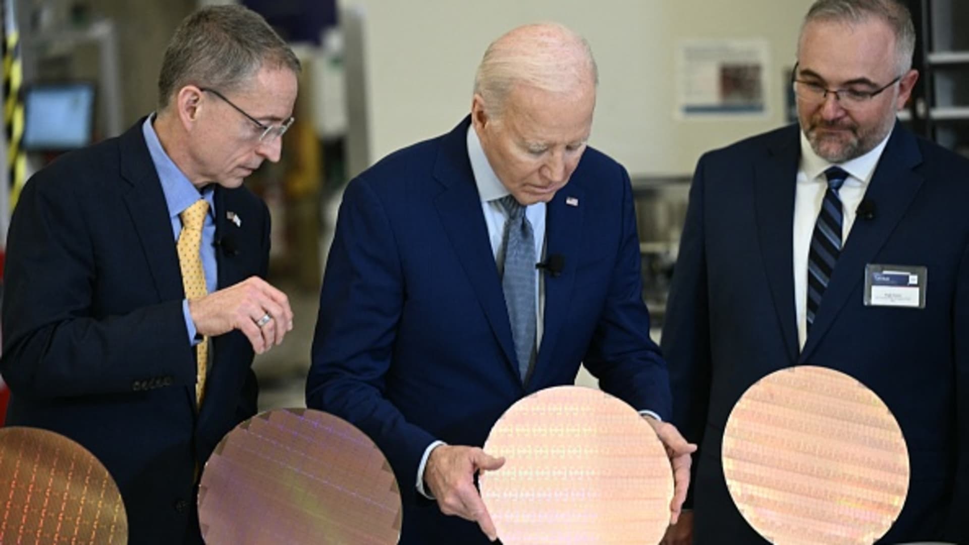 US President Joe Biden (C) stands behind a table, next to Intel's CEO Pat Gelsinger (L) as they look at wafers while touring the Intel Ocotillo Campus in Chandler, Arizona, on March 20, 2024.