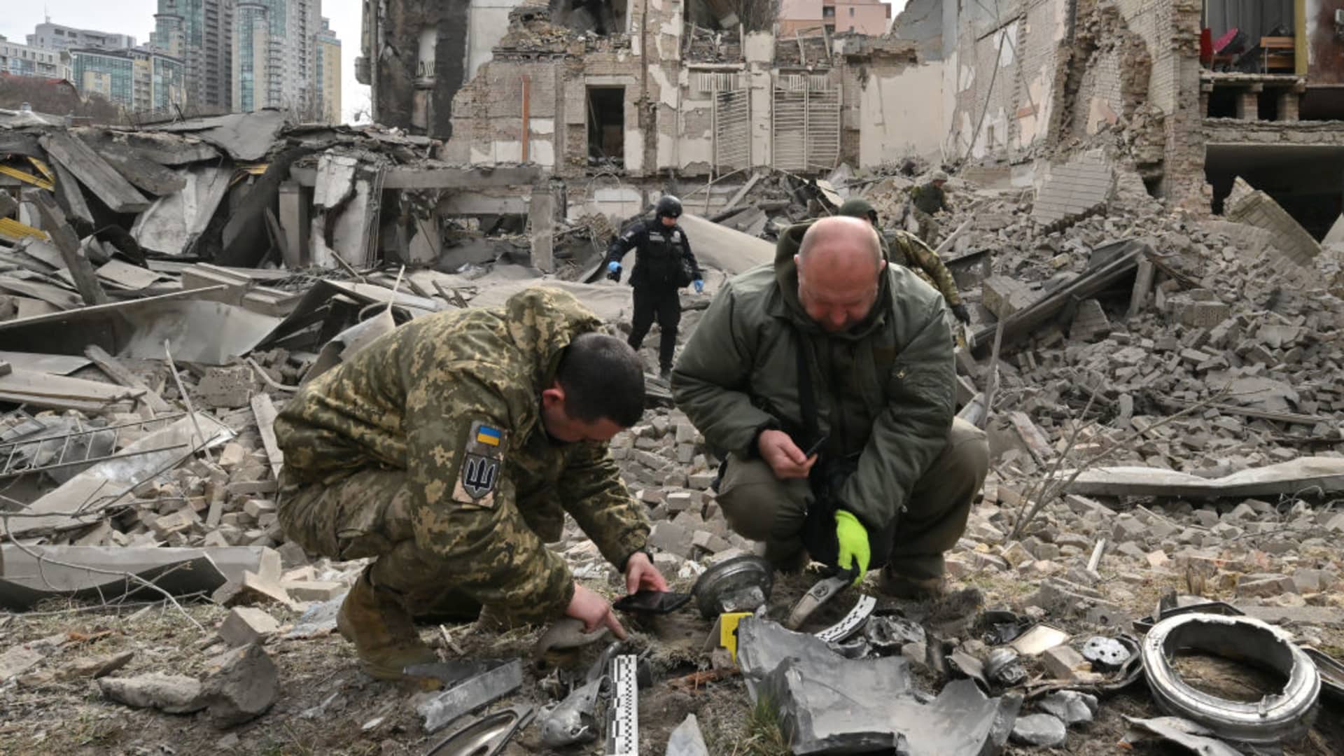 Ukrainian law enforcement officers examine fragments of a rocket at the site of a missile attack in Kyiv on March 25, 2024, amid the Russian invasion of Ukraine. Five people including a teenage girl were injured on March 25, 2024 during a Russian missile attack on Kyiv, where falling debris also damaged at least two buildings in central districts.