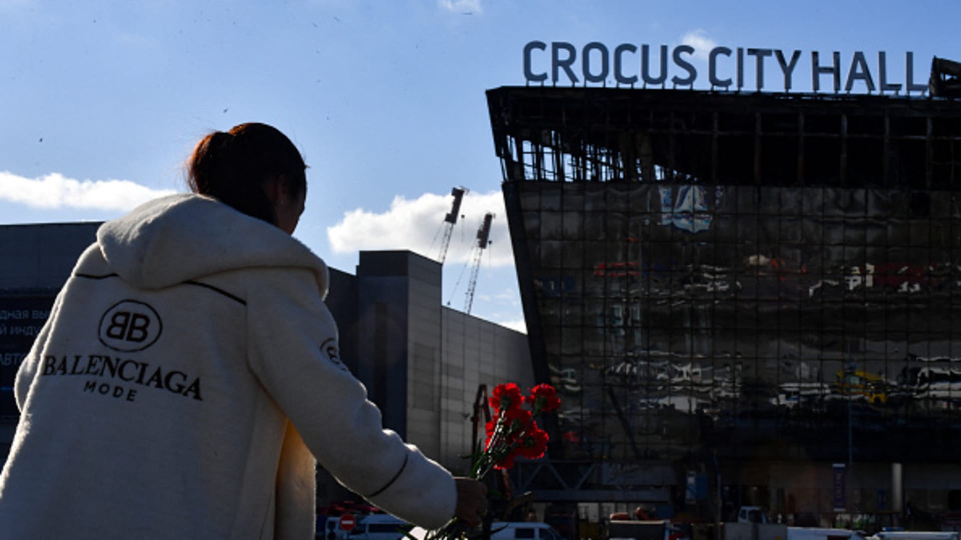 People bring flowers to a makeshift memorial in front of the burnt-out Crocus City Hall concert venue in Krasnogorsk, outside Moscow, on March 25, 2024. 