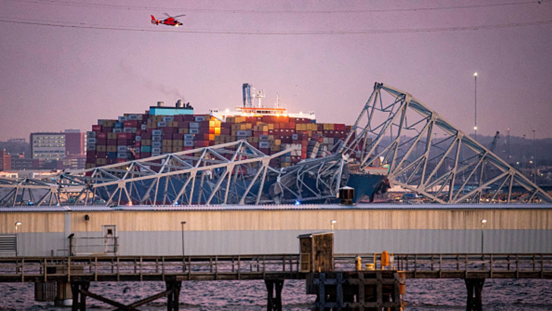 A US Coast Guard helicopter flies over the Dali container vessel after it struck the Francis Scott Key Bridge that collapsed into the Patapsco River in Baltimore, Maryland, US, on Tuesday, March 26, 2024. The commuter bridge collapsed after being rammed by the Dali ship, causing vehicles to plunge into the water. Photographer: Al Drago/Bloomberg via Getty Images