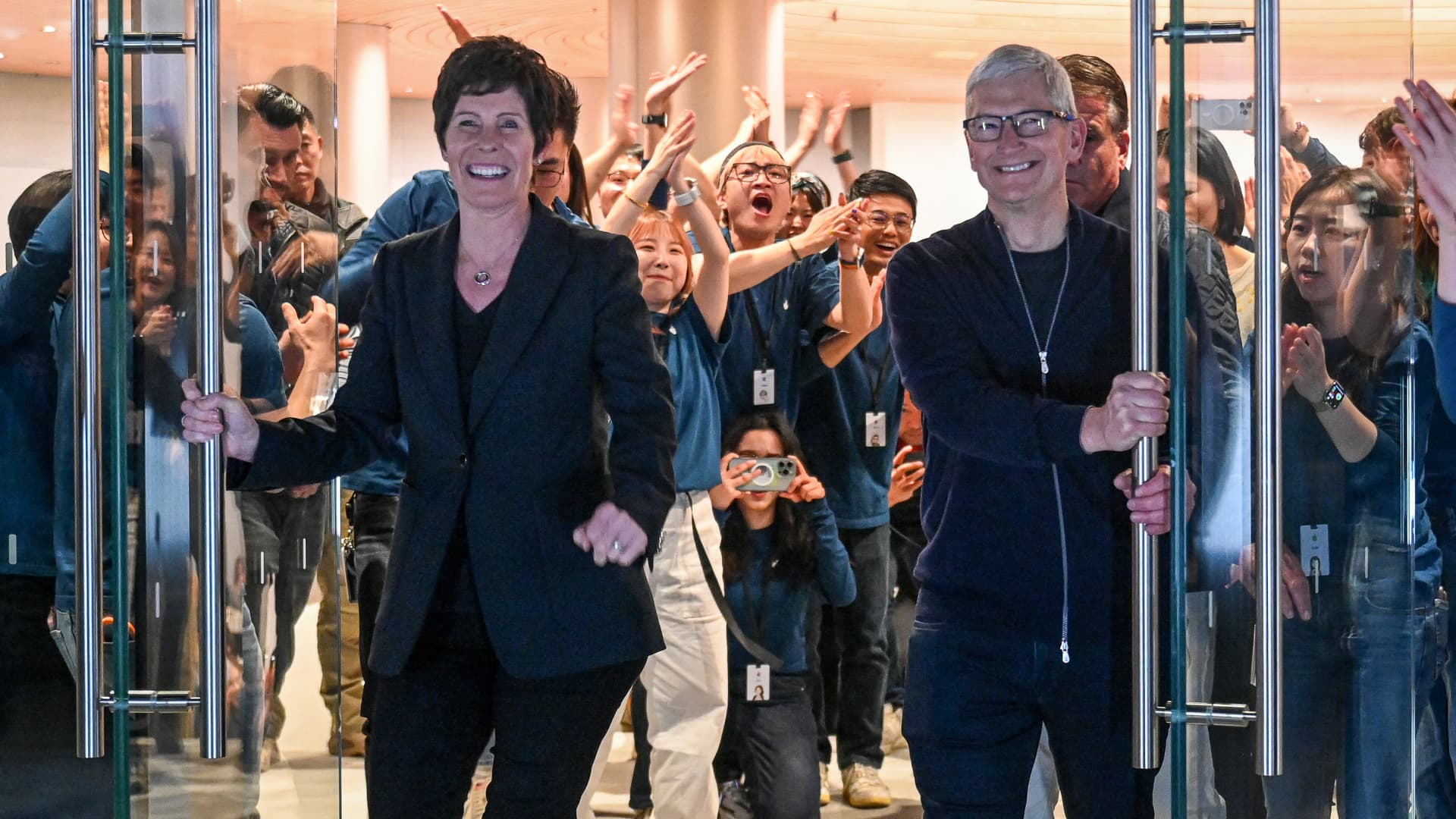 Apple's Chief Executive Officer Tim Cook (R) and Senior Vice President of Retail Deirdre O'Brien open the doors during the opening of Shanghai's new Apple retail store in Shanghai on March 21, 2024. Chinese Apple superfans jostled to enter the smartphone maker's newest store as it opened on March 21 night.