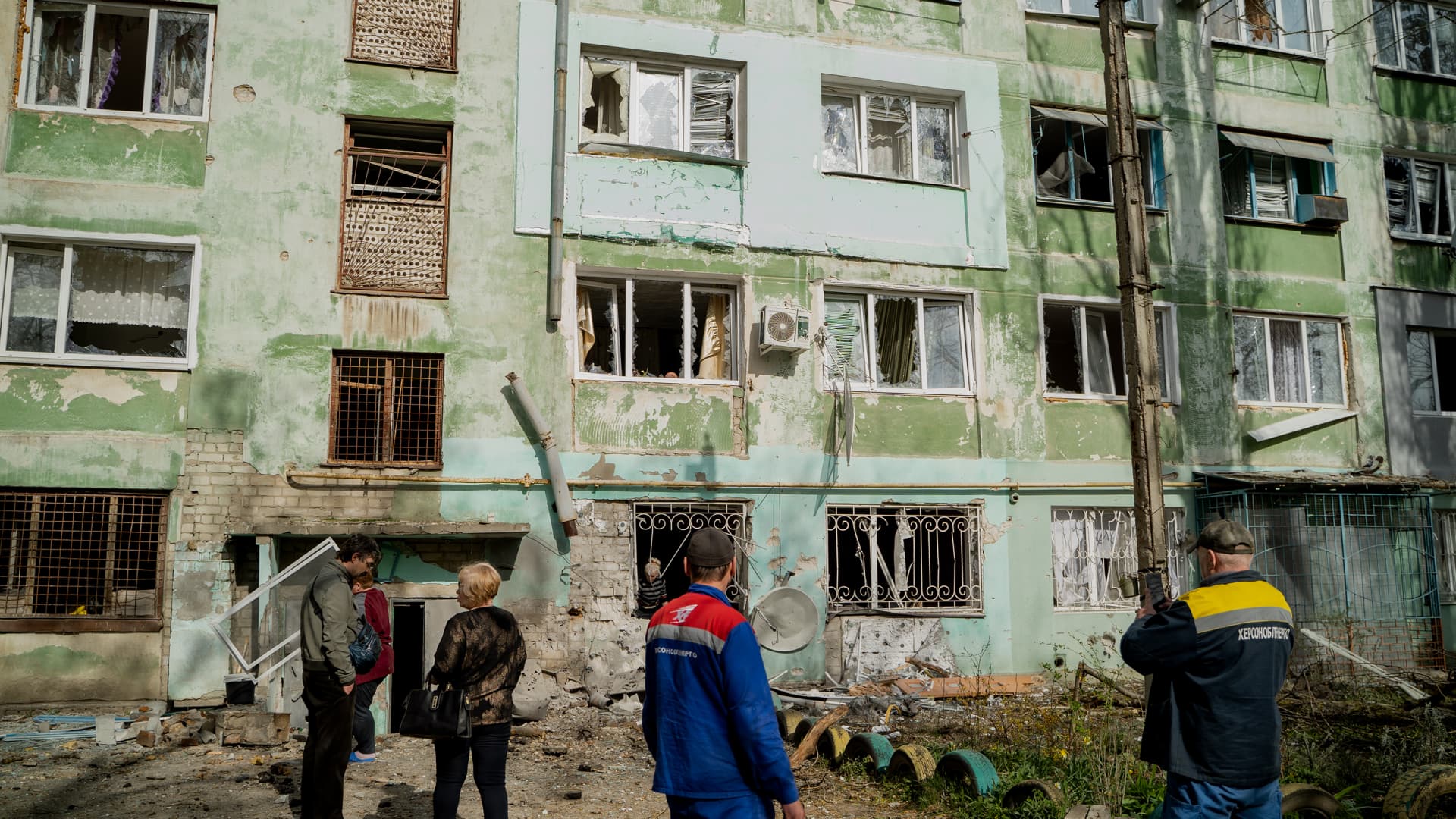 People stand near a damaged residential high-rise building on April 5, 2024 in Kherson, Ukraine. 