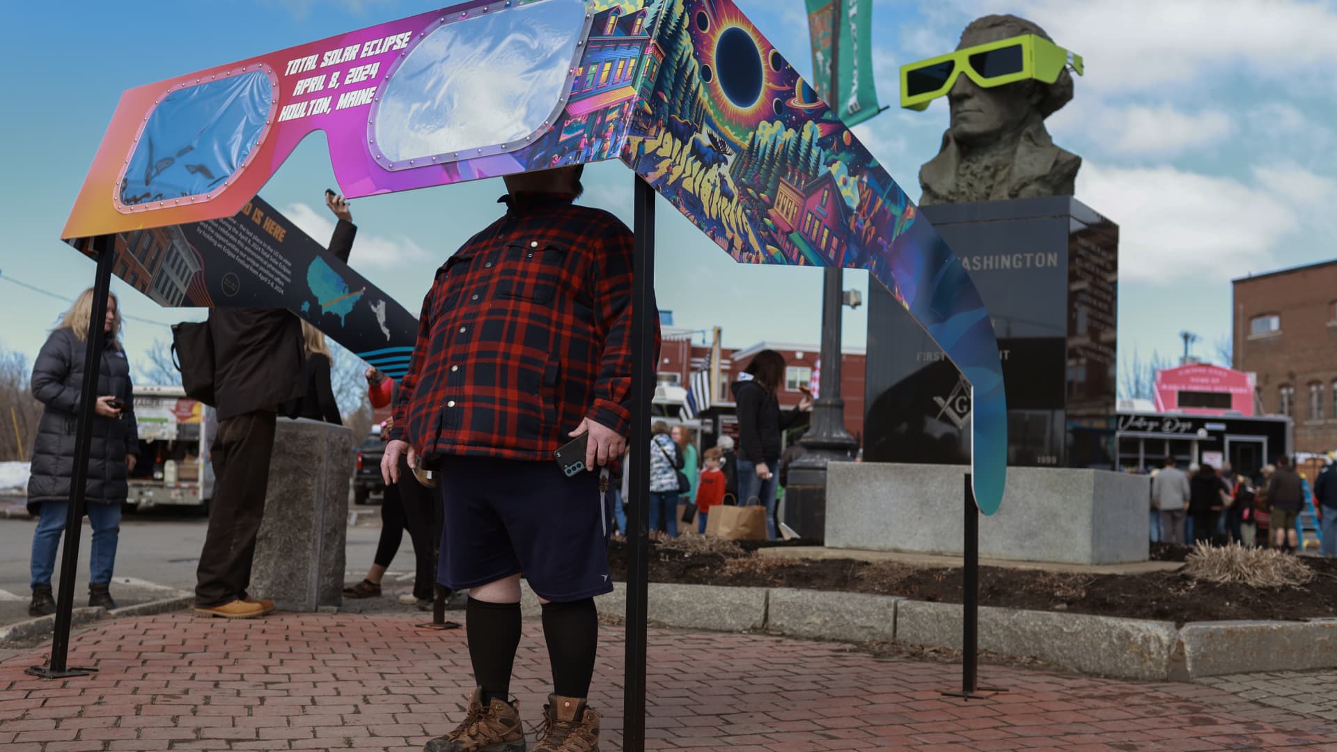 \Visitors look through a pair of oversized eclipse glasses set up in the town square on April 07, 2024, in Houlton, Maine. 