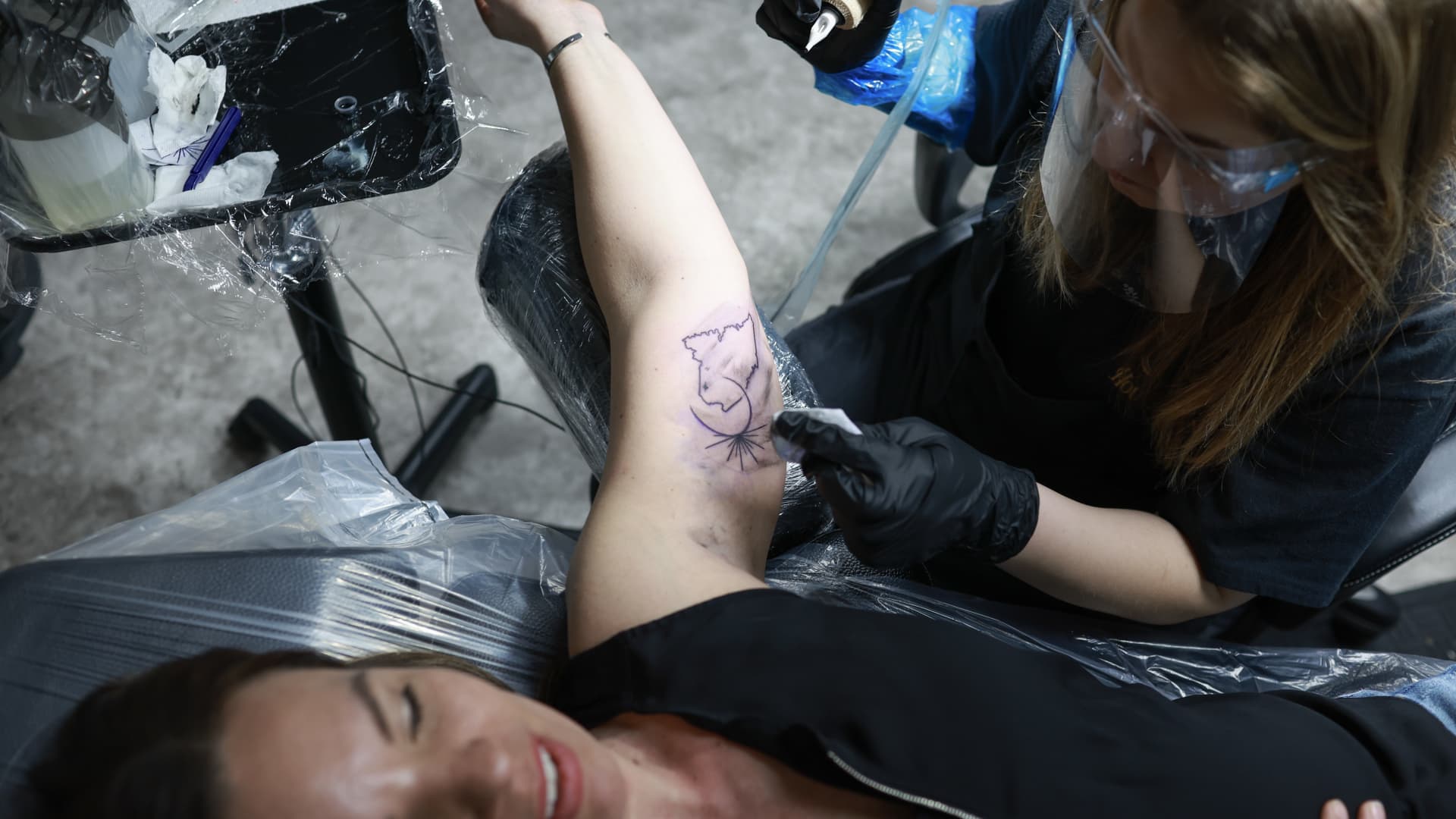 Dawn MacDonald (R), the owner of Crowe's Tattoos, places an eclipse tattoo on the arm of Morgan Flewelling (L) on April 07, 2024, in Houlton, Maine. 