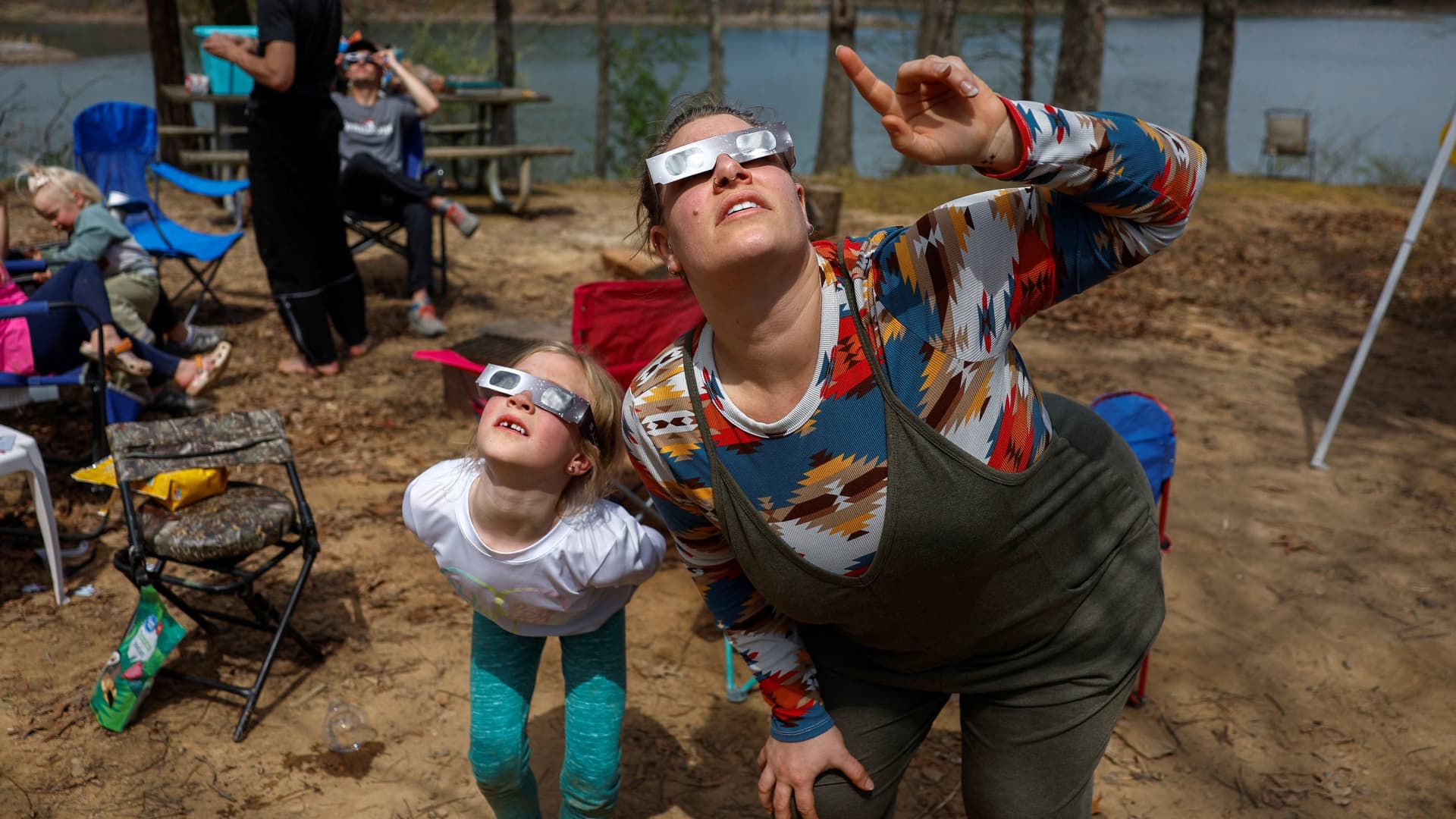 Brittany Sunderman and Gianna Debenham, 6, from Effingham, Illinois, and other members of the Debenham family who travelled from Utah and Las Vegas to experience the total solar eclipse together, try out their eclipse viewing glasses at their campsite a day ahead of the event at Camp Carew in Makanda, Illinois, U.S., April 7, 2024.