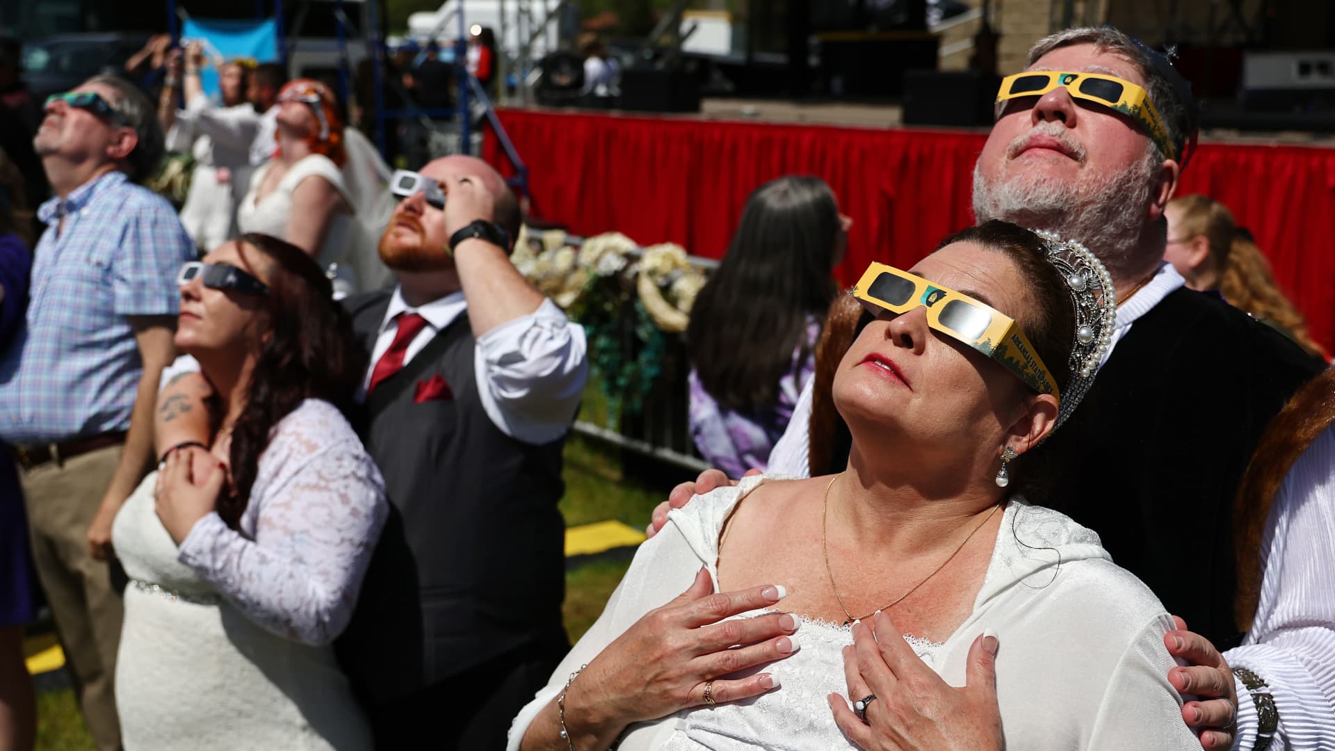 Couples view the solar eclipse during a mass wedding at the Total Eclipse of the Heart festival on April 8, 2024 in Russellville, Arkansas. 