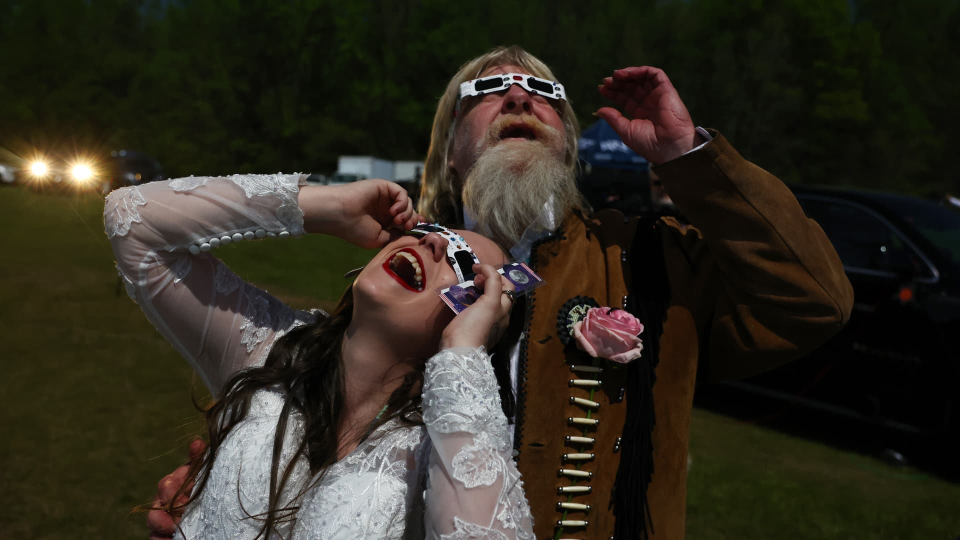 A bride and groom view the solar eclipse amid a darkened sky after marrying at a mass wedding at the Total Eclipse of the Heart festival on April 8, 2024 in Russellville, Arkansas.
