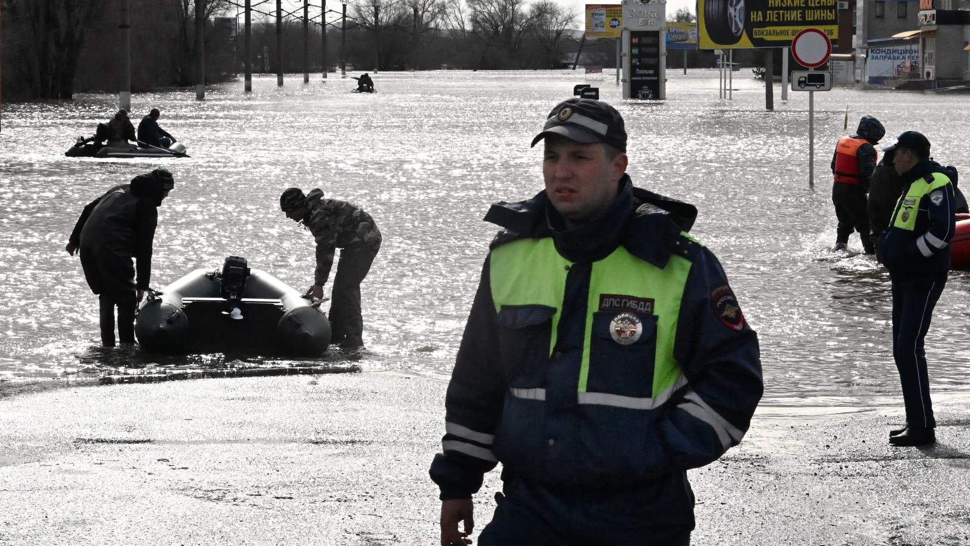 Traffic police officers stand on a flooded street as rescuers on inflatable boats evacuate residents of the city of Orsk, Russia's Orenburg region, southeast of the southern tip of the Ural Mountains, on April 8, 2024.