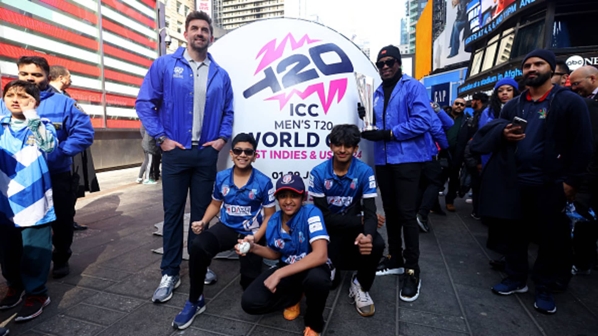 Cricketers Liam Plunkett, center left, and Dwayne Bravo, center right, pose for pictures with children during a media day to mark 100 days to go until the ICC Men's T20 World Cup 2024 co-hosted in the West Indies and the U.S., at Times Square in New York City, Feb. 22, 2024.