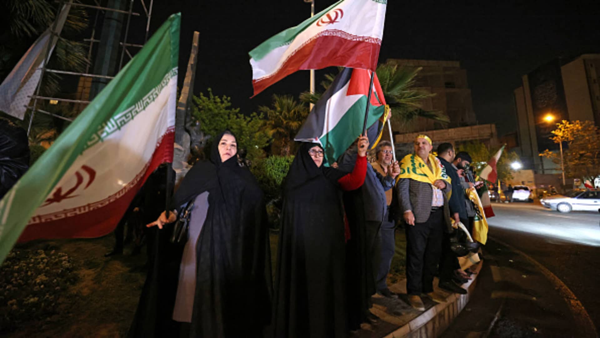 Demonstrators wave Iran's flag and a Palestinian flag as they gather at Palestine Square in Tehran on April 14, 2024, after Iran launched a drone and missile attack on Israel. 